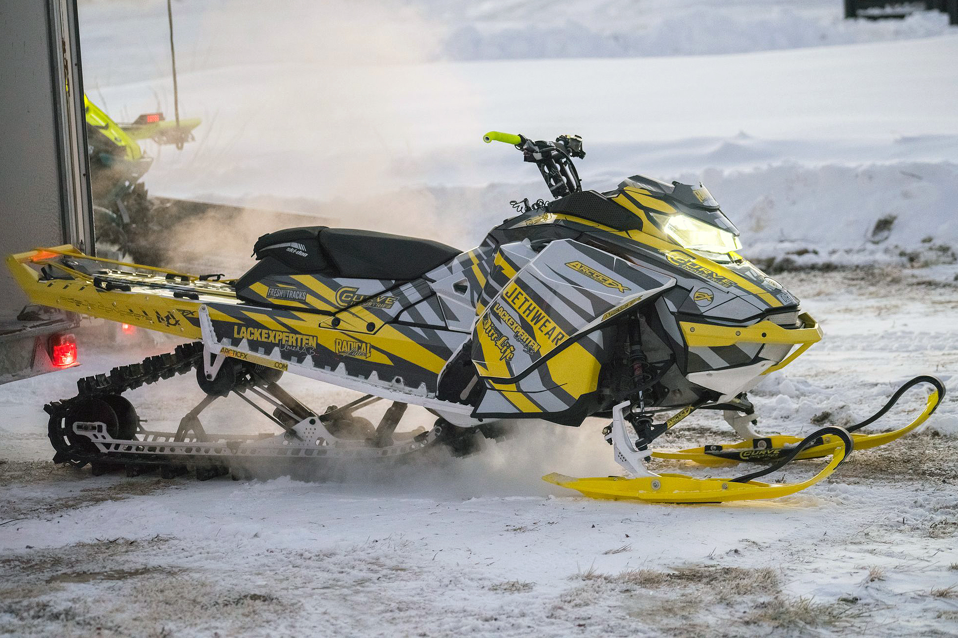A Ski-Doo Gen4 Narrow Body snowmobile with a gray and yellow Relay custom vinyl wrap.