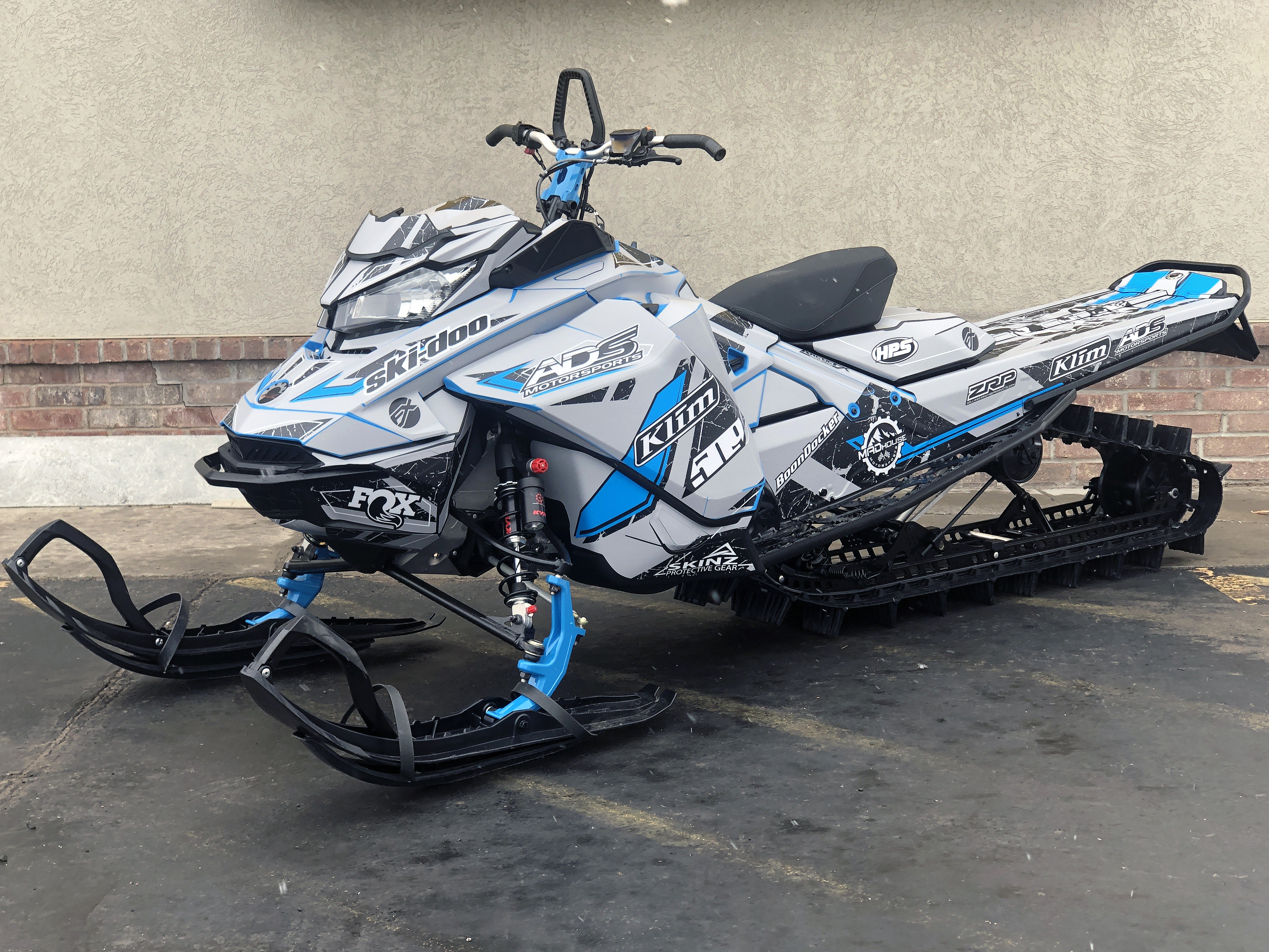 A Ski-Doo Gen4 Narrow Body snowmobile with a gray, black, and octane blue Rogue custom vinyl wrap.