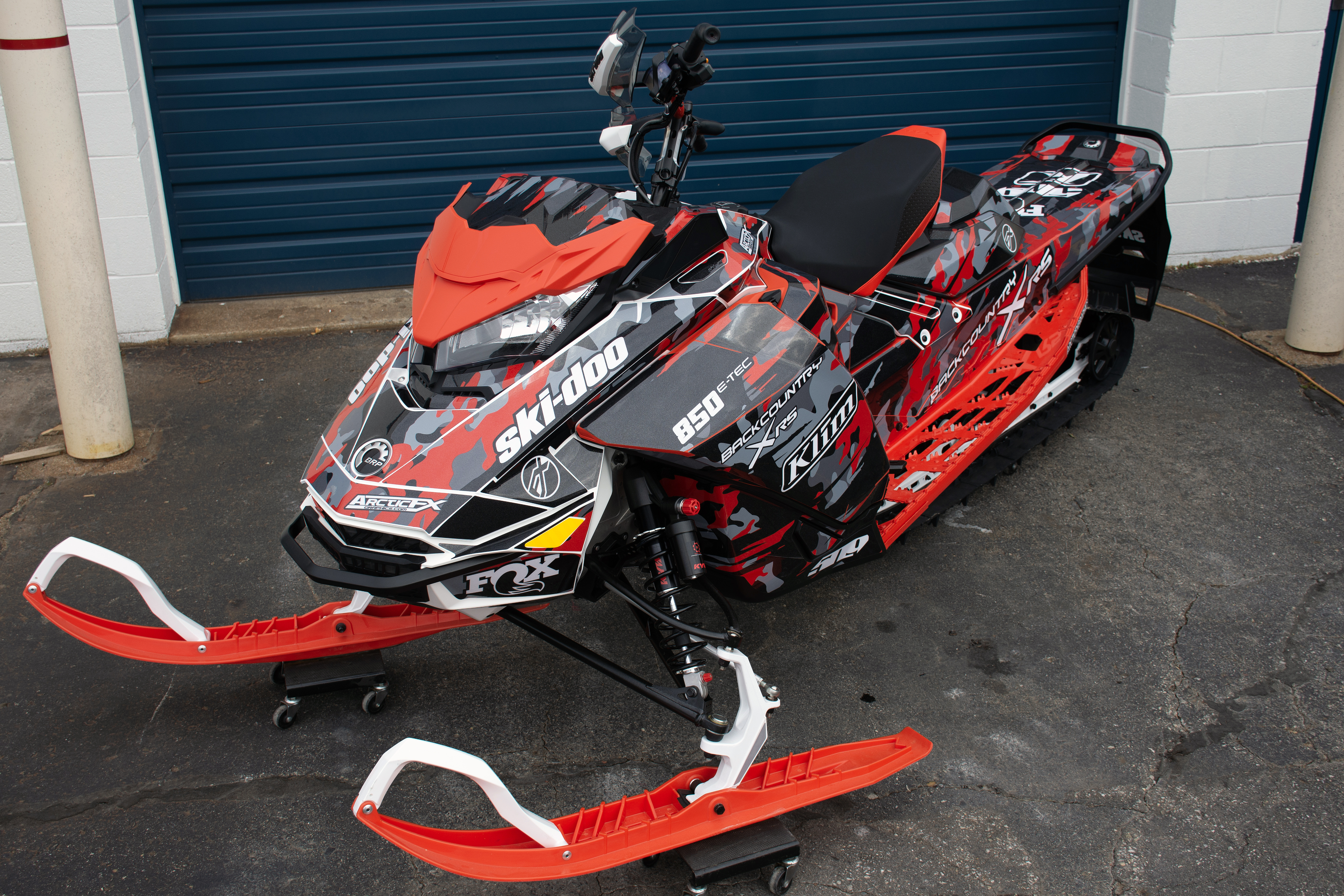 A Ski-Doo Gen4 Narrow Body snowmobile with a red, gray, and black RR Camo custom vinyl wrap.