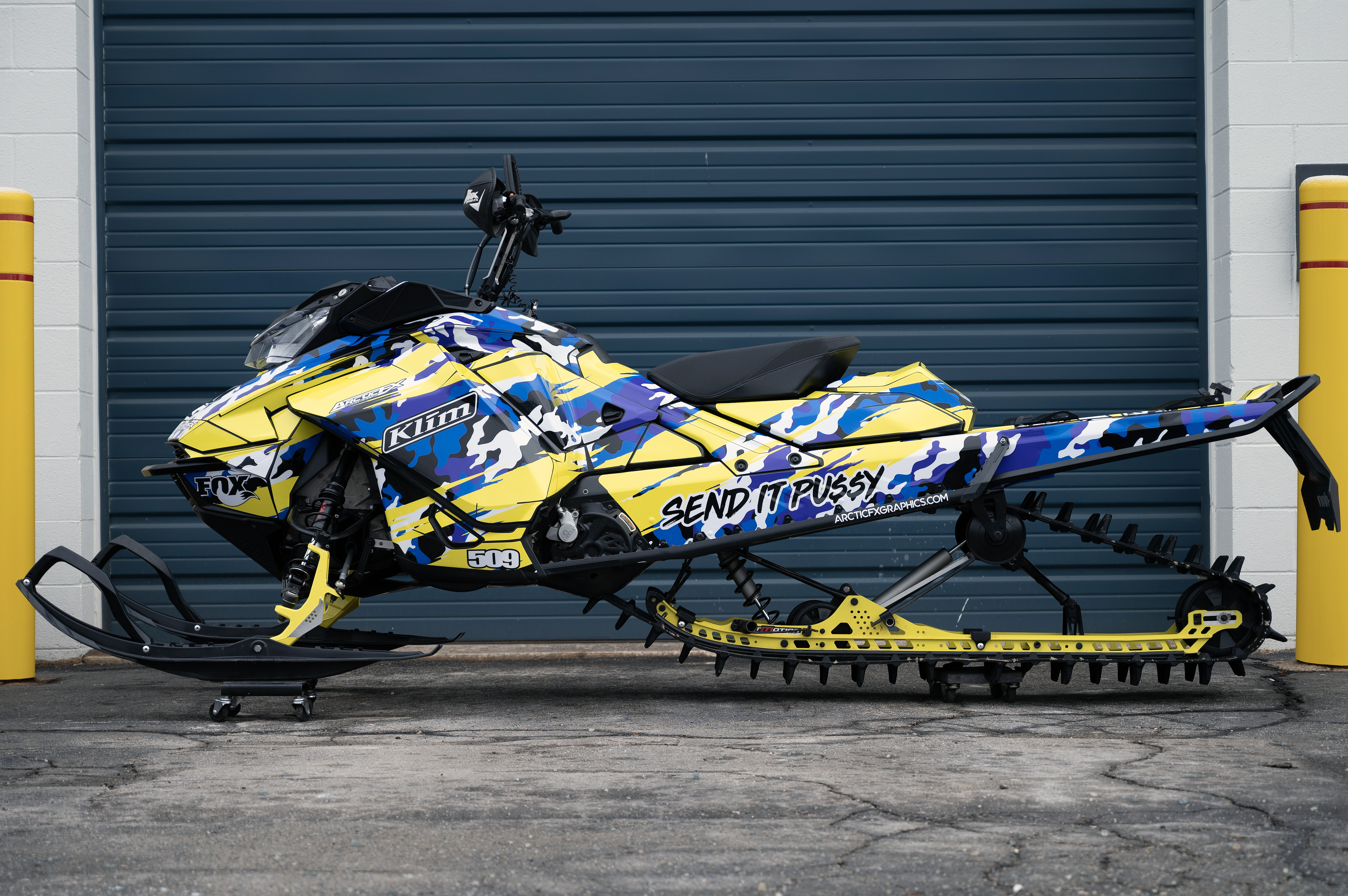 A Ski-Doo Gen4 Narrow Body snowmobile with a yellow, purple, and black RR Camo custom vinyl wrap.