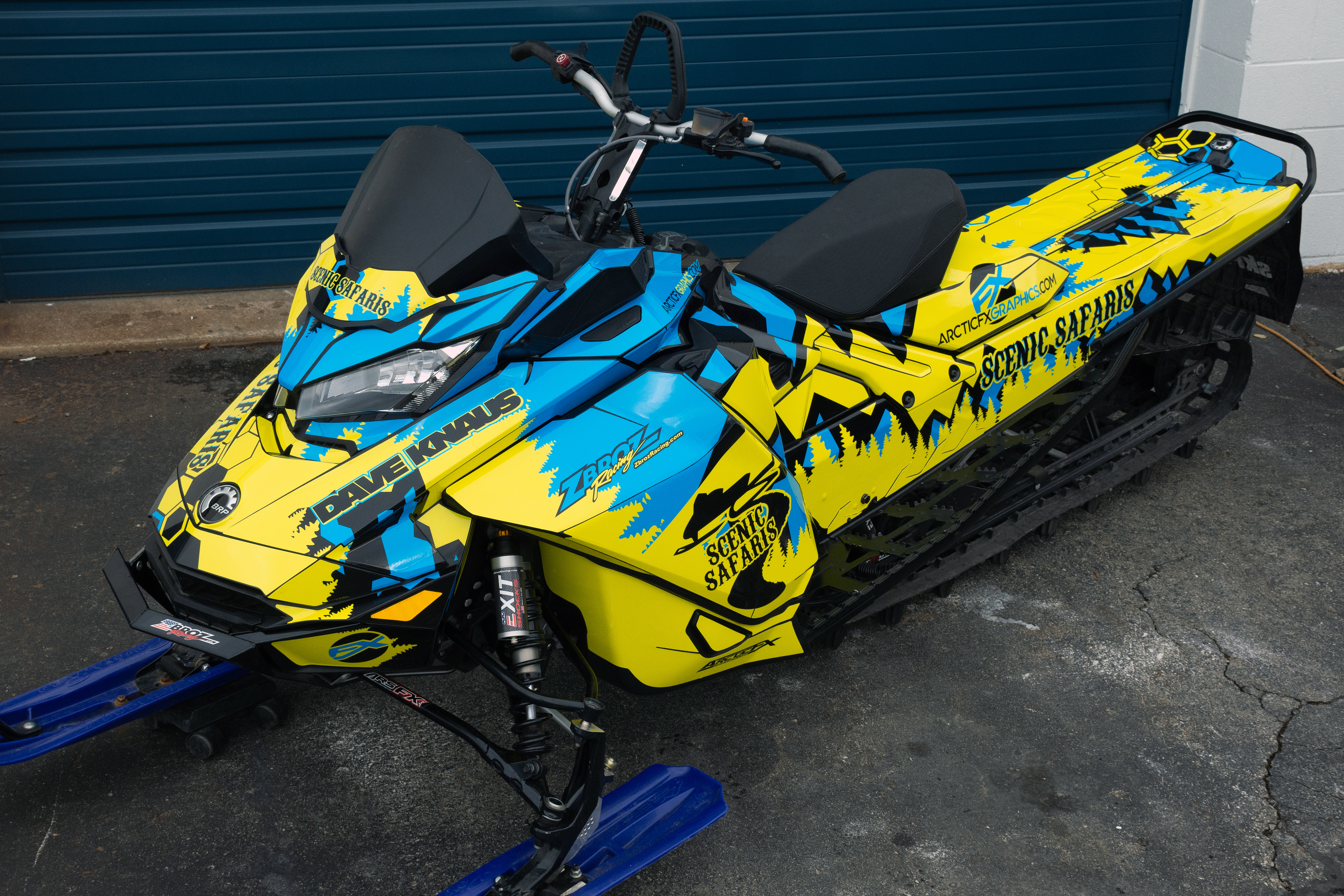 A Ski-Doo Gen4 Narrow Body snowmobile with a octane blue, yellow, and black Scenic Safaris custom vinyl wrap.