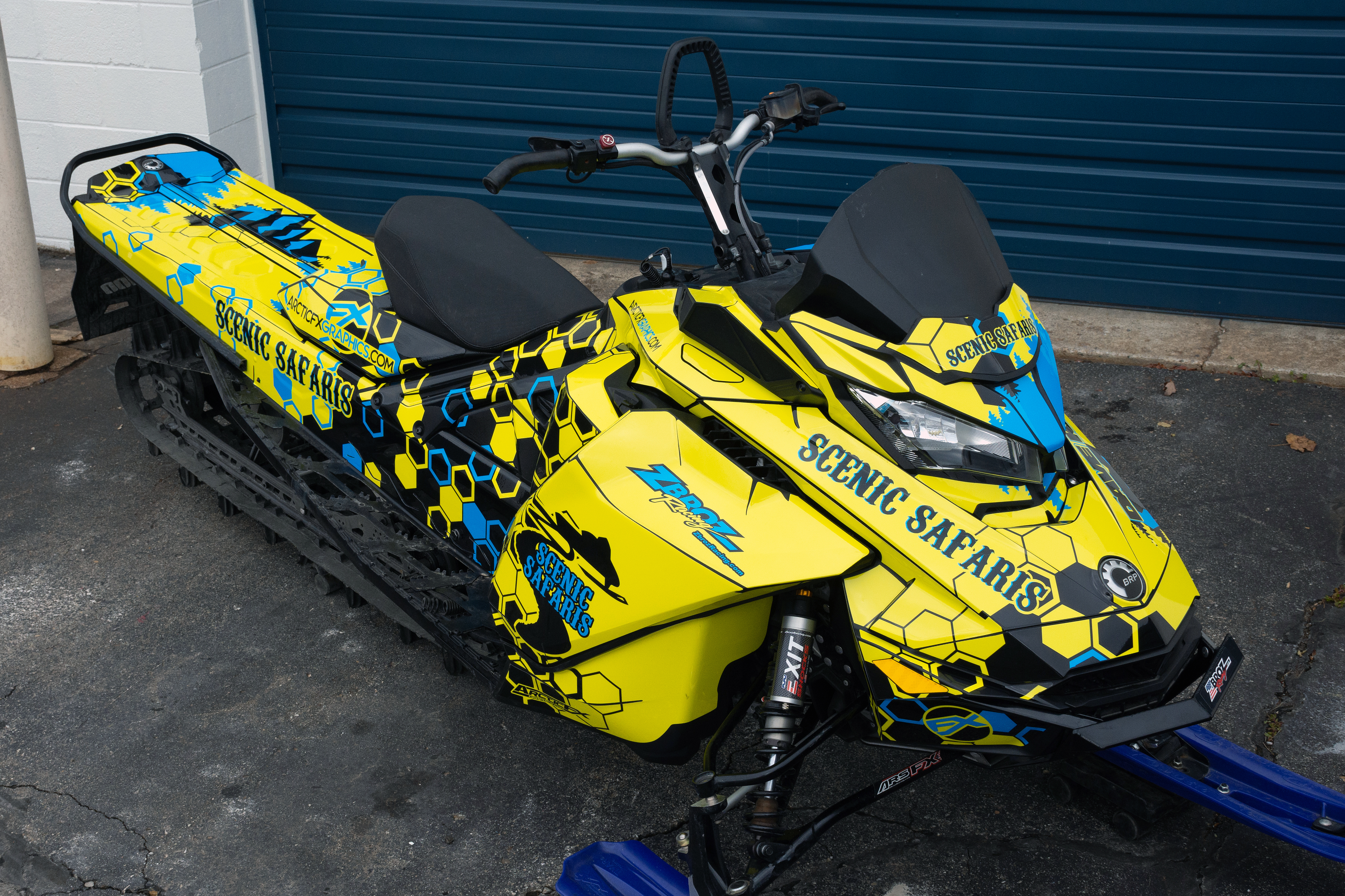 A Ski-Doo Gen4 Narrow Body snowmobile with a octane blue, yellow, and black Scenic Safaris custom vinyl wrap.