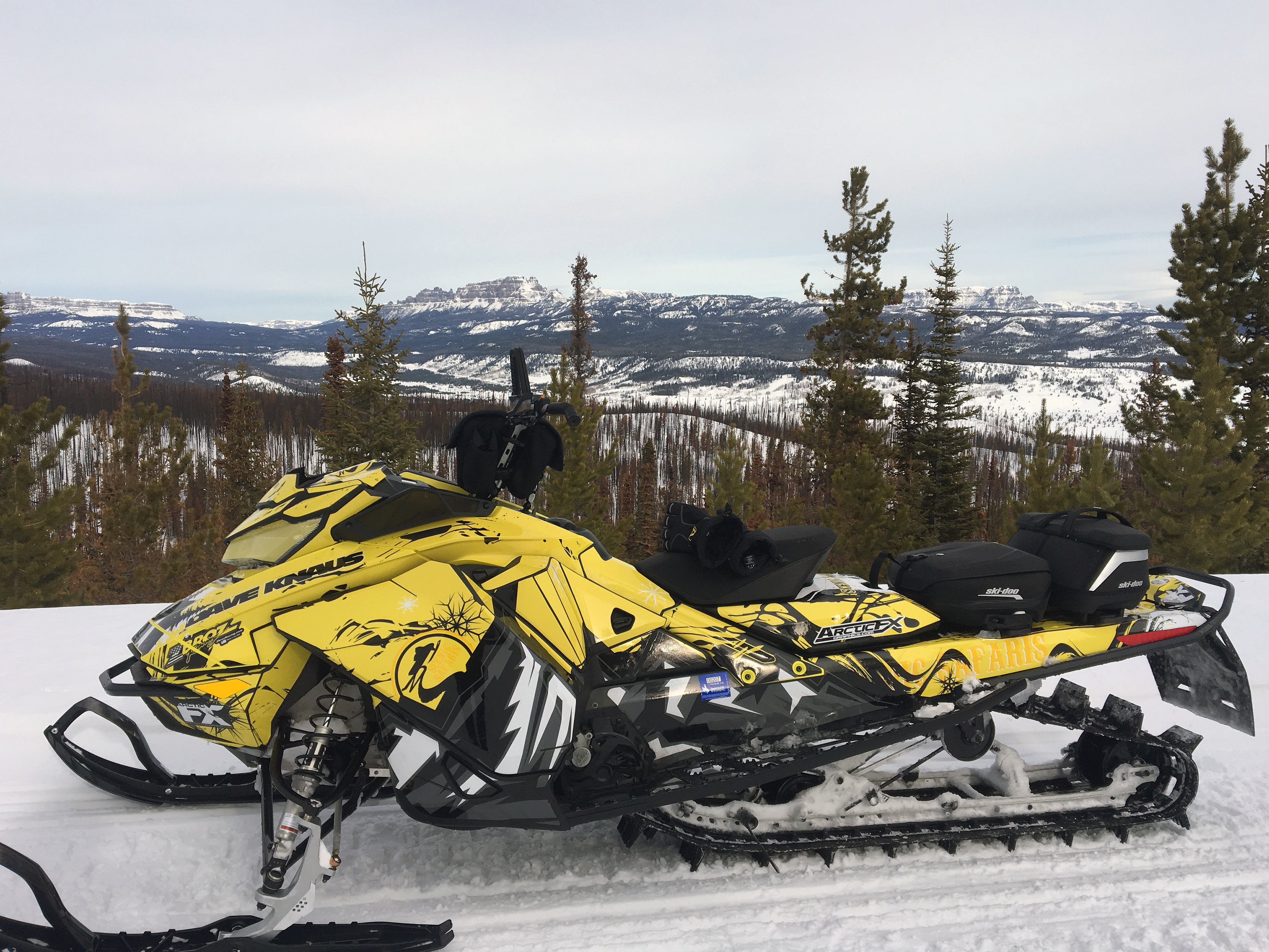 A Ski-Doo Gen4 Narrow Body snowmobile with a octane white, yellow, and black Scenic Safaris custom vinyl wrap.