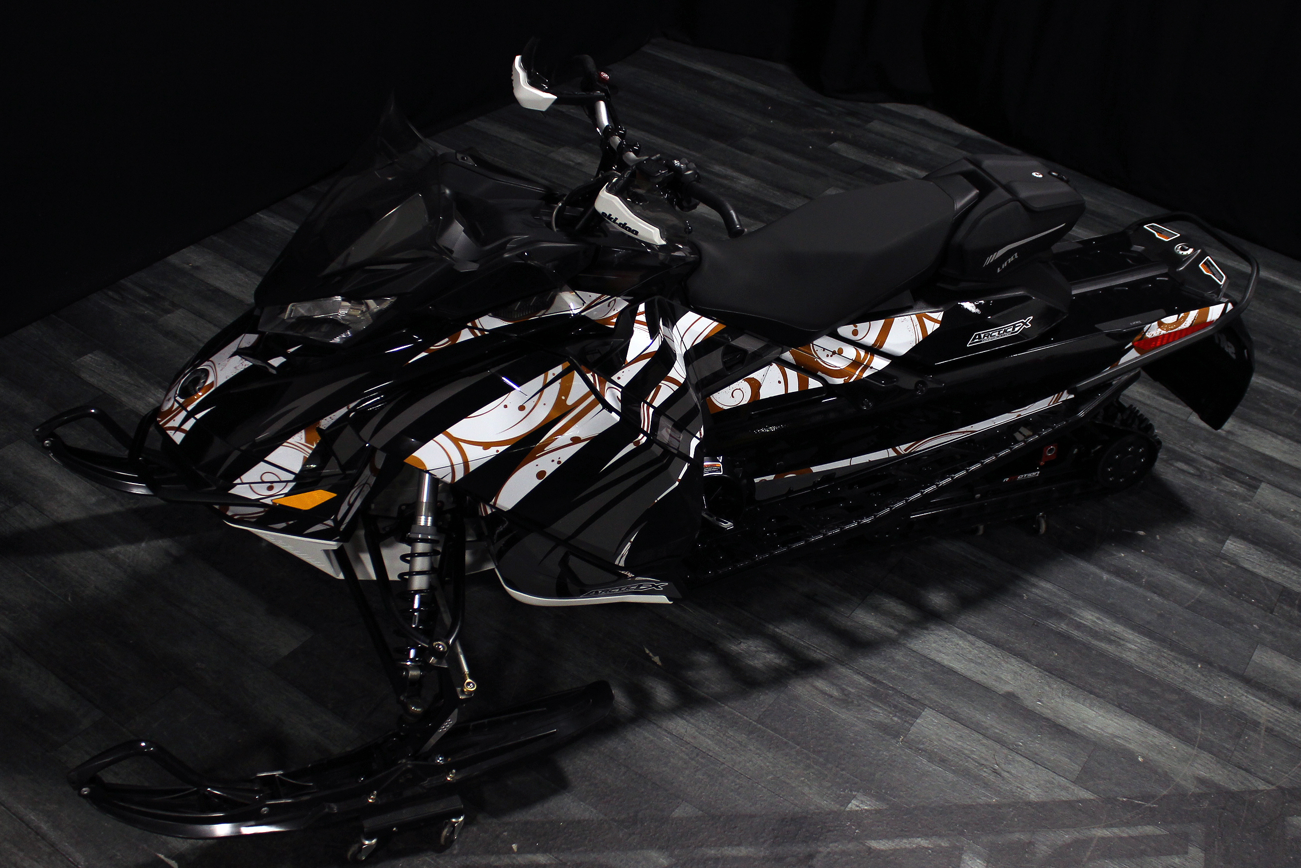A Ski-Doo Gen4 Narrow Body snowmobile with a white, tan, and black Surge custom vinyl wrap.