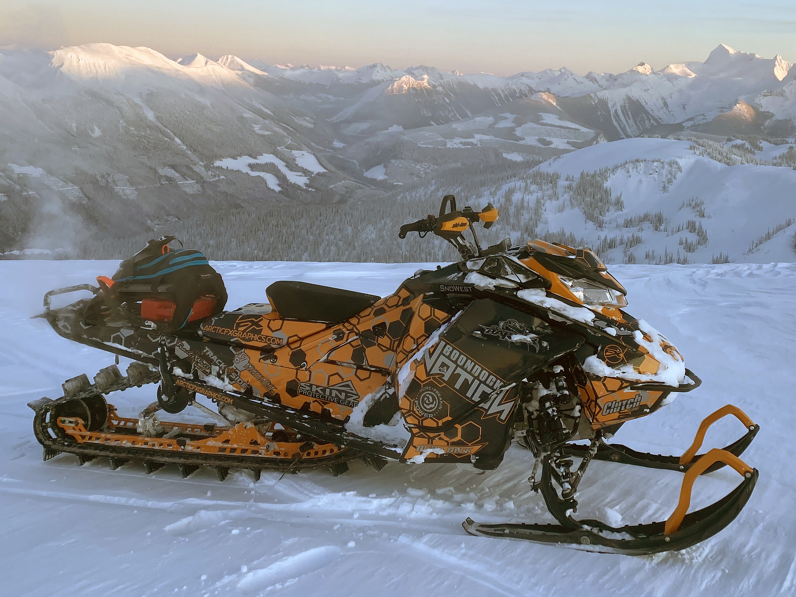 A Ski-Doo Gen4 Narrow Body snowmobile with a black, orange, and gray Sync custom vinyl wrap.