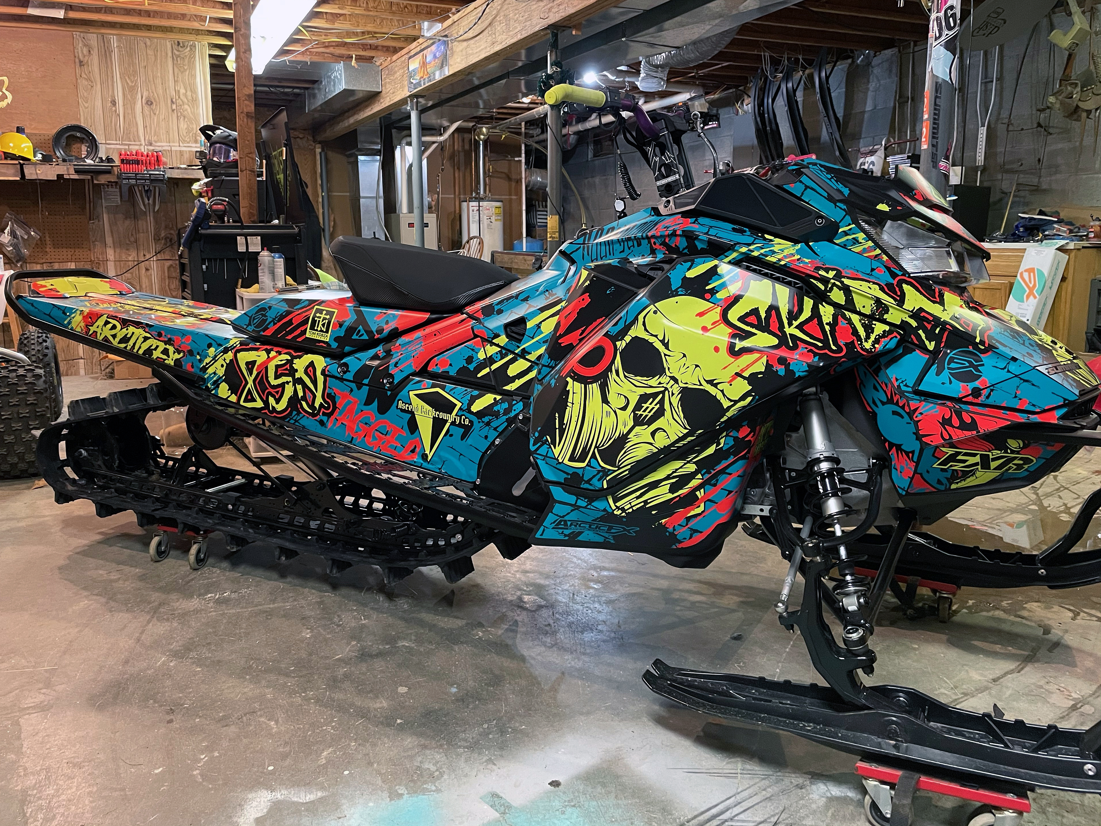 A Ski-Doo Gen4 Narrow Body snowmobile with a teal, manta, and red Tagged custom vinyl wrap.