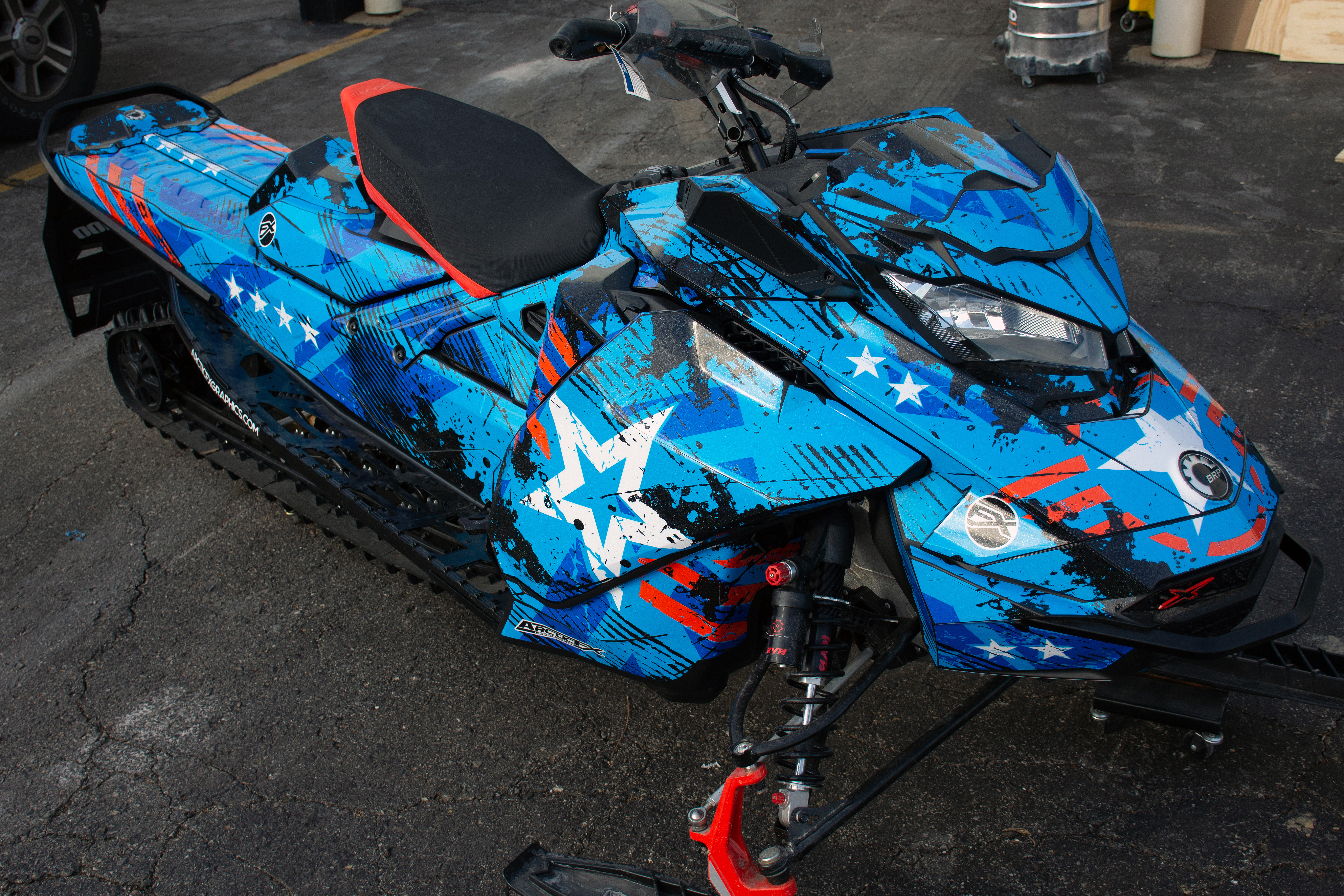 A Ski-Doo Gen4 Narrow Body snowmobile with a octane blue, red, and black Wartorn custom vinyl wrap.