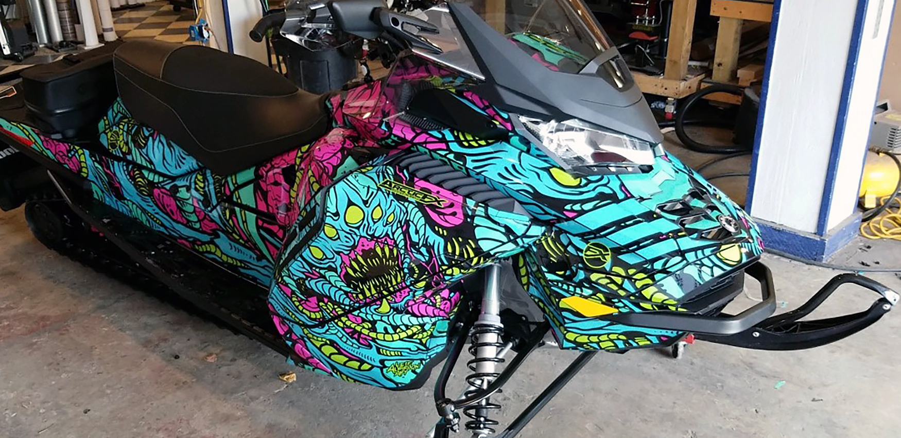 A Ski-Doo Gen4 Wide Body snowmobile with a aqua, pink and manta Leif Alvarsson Area 51 custom vinyl wrap.
