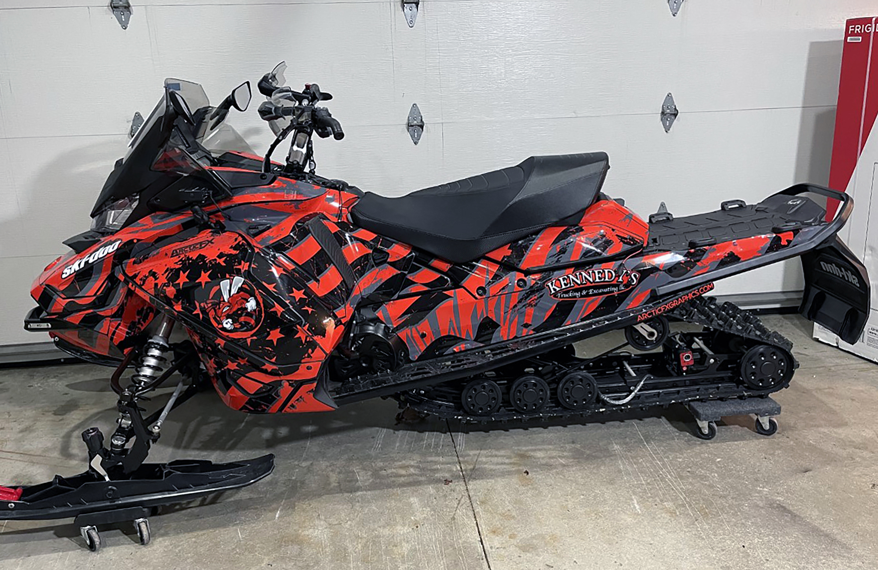 A Ski-Doo Gen4 Wide Body snowmobile with a red, gray, and black American Flag custom vinyl wrap.