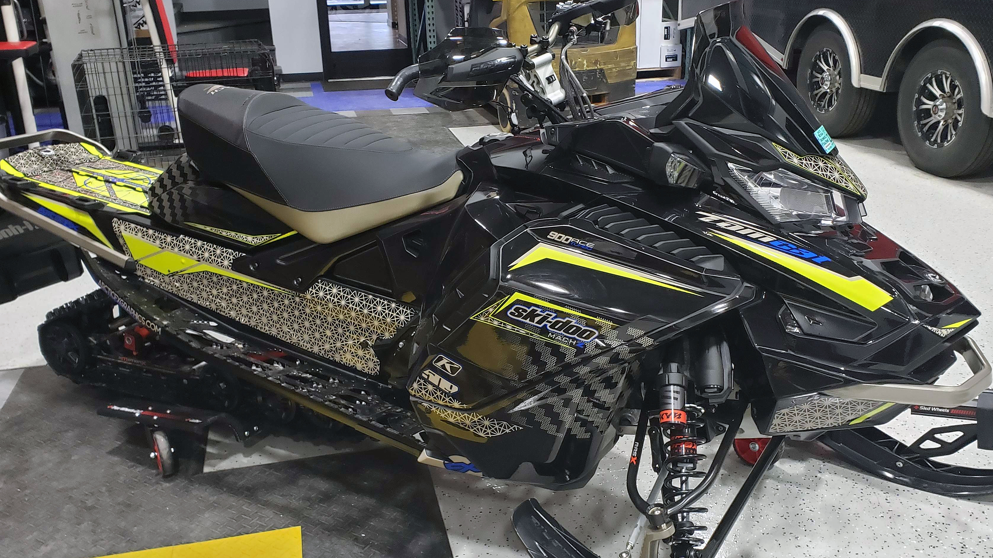 A Ski-Doo Gen4 Wide Body snowmobile with a lime squeeze, gray, and black Atomic custom vinyl wrap.