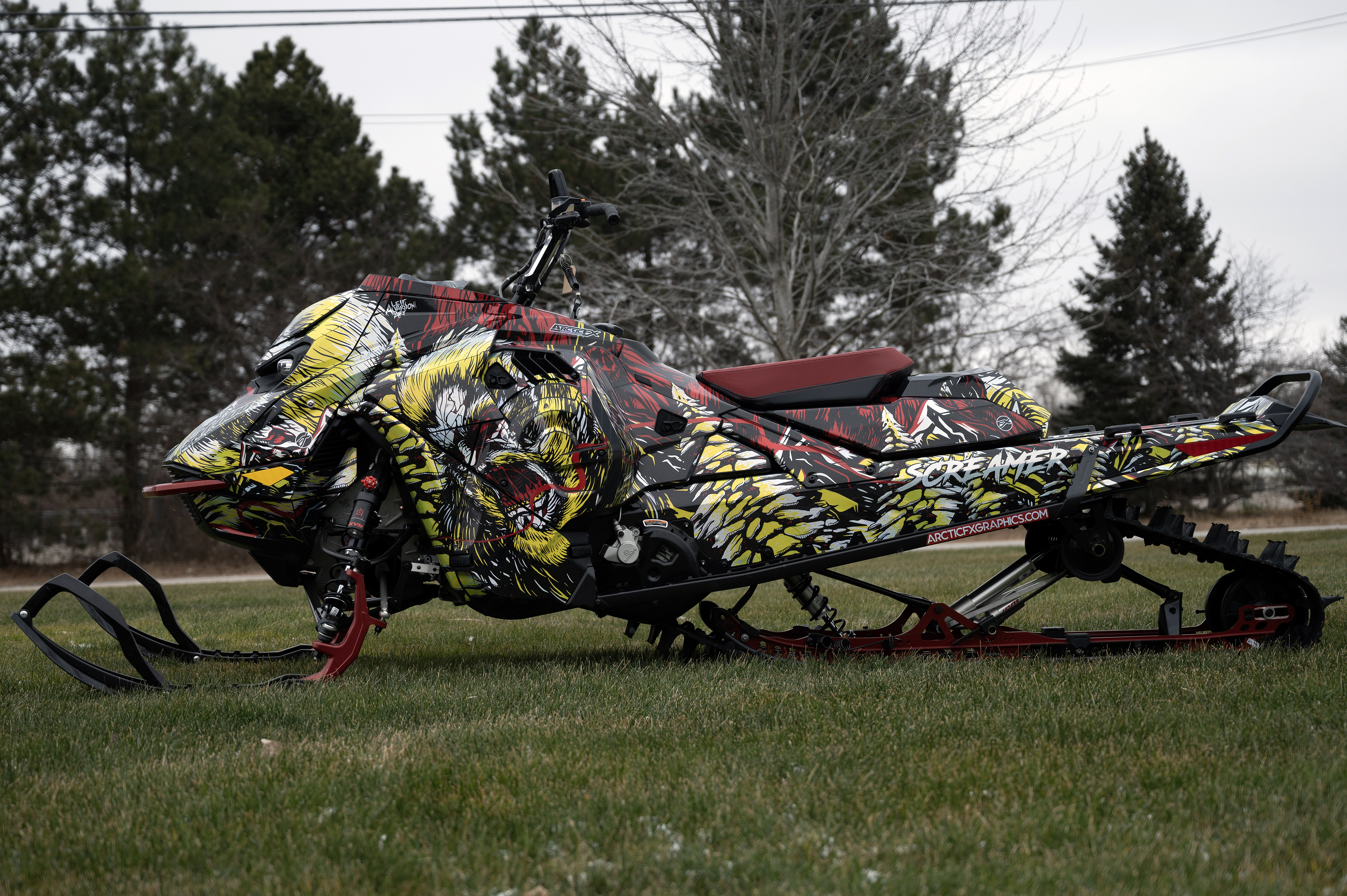 A Ski-Doo Gen5 Mountain snowmobile with a chrome, red, black, and lime squeeze Leif Alvarsson Tree Slayer custom vinyl wrap.