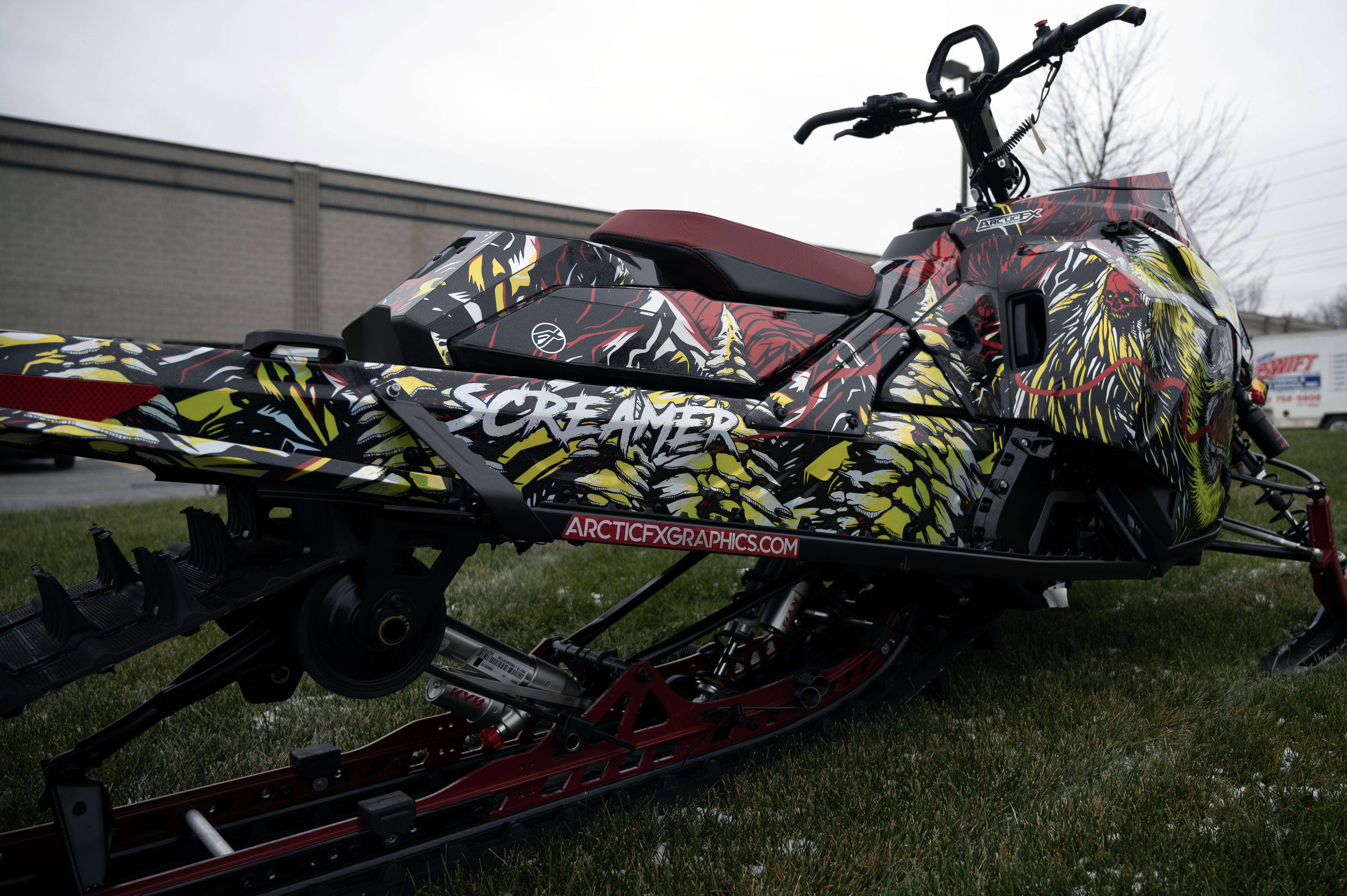 A Ski-Doo Gen5 Mountain snowmobile with a chrome, red, black, and lime squeeze Leif Alvarsson Tree Slayer custom vinyl wrap.