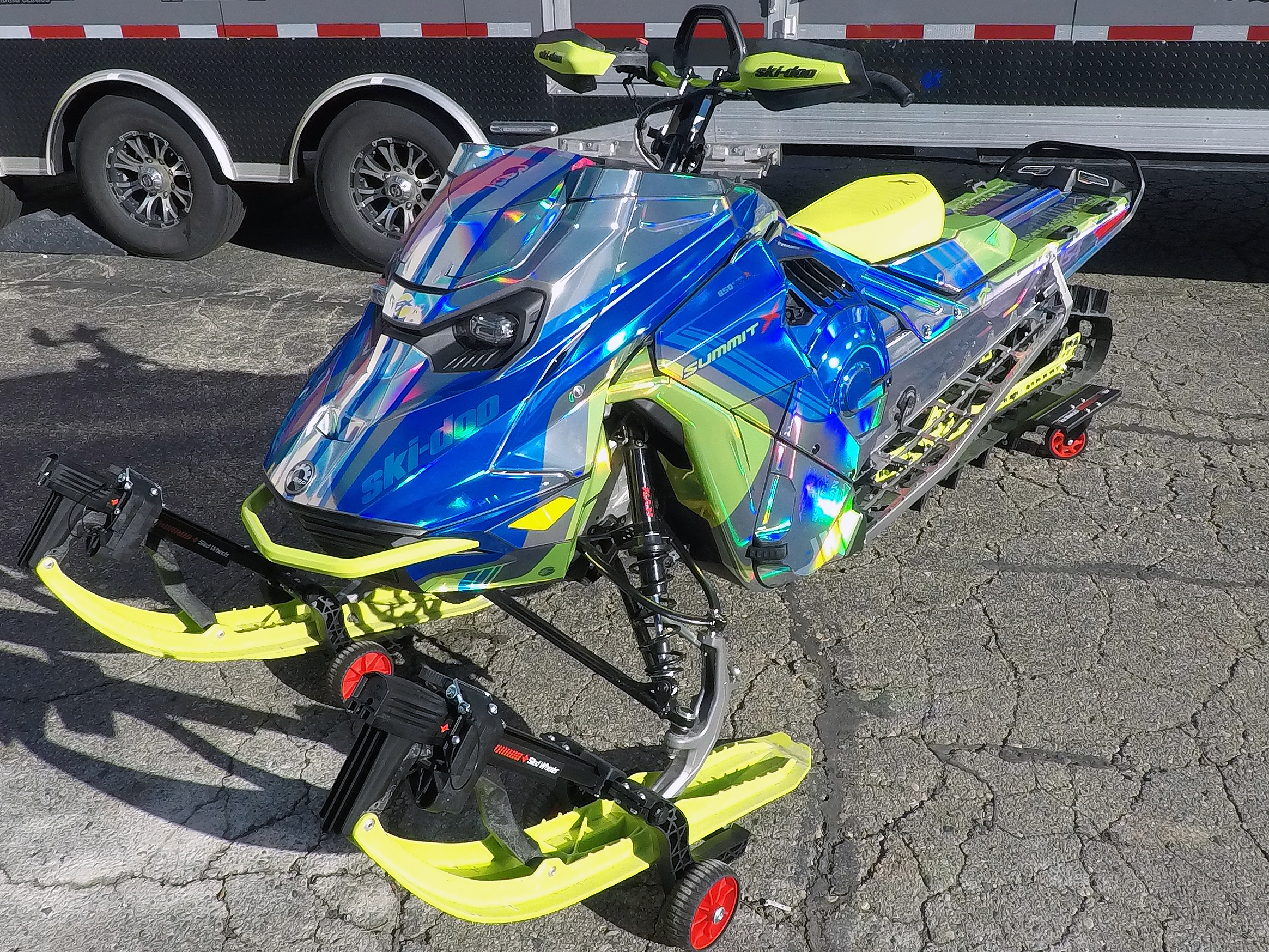 A Ski-Doo Gen5 Mountain snowmobile with a chrome, blue, and lime squeeze Cobra MC custom vinyl wrap.