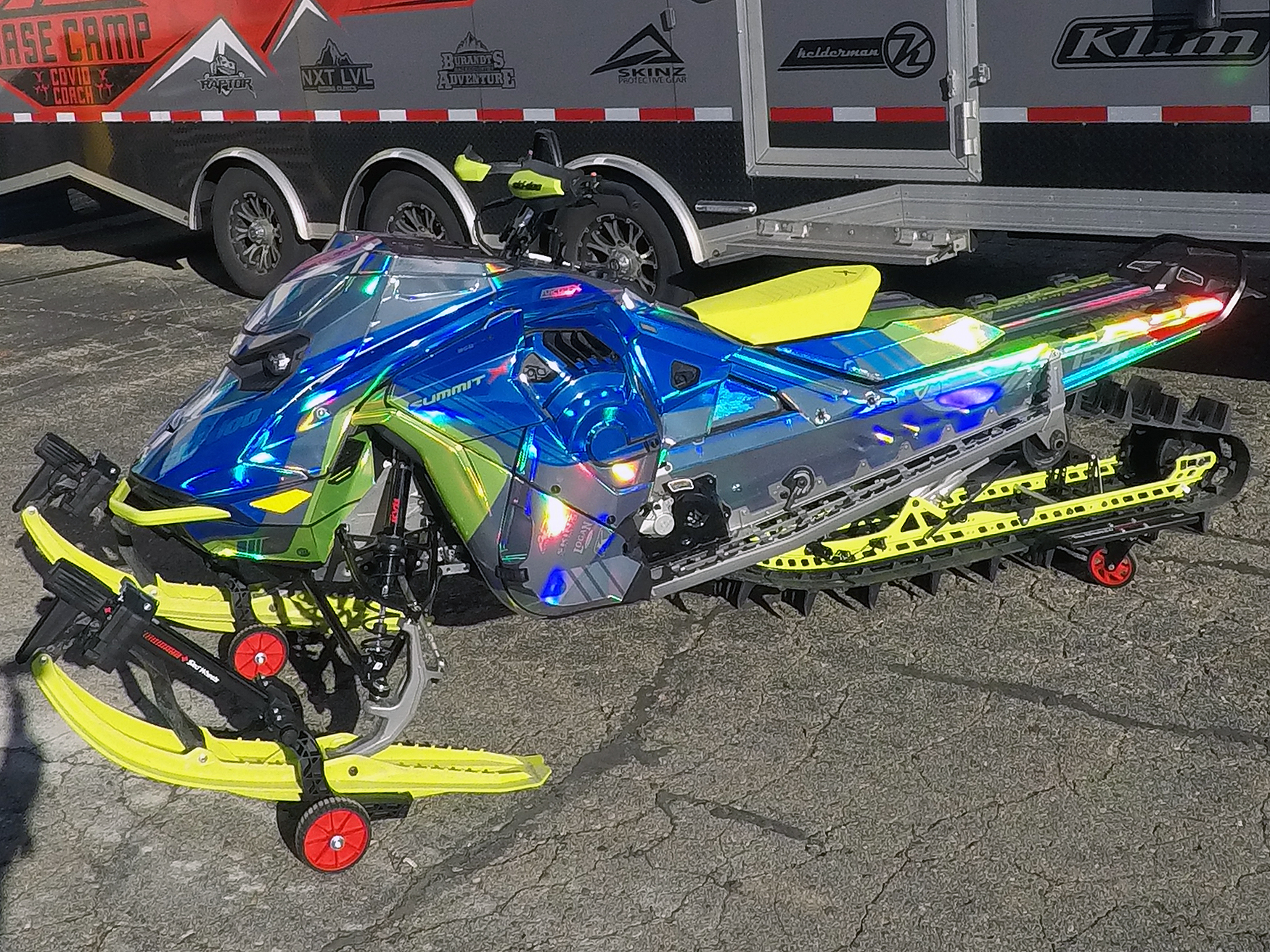 A Ski-Doo Gen5 Mountain snowmobile with a chrome, blue, and lime squeeze Cobra MC custom vinyl wrap.