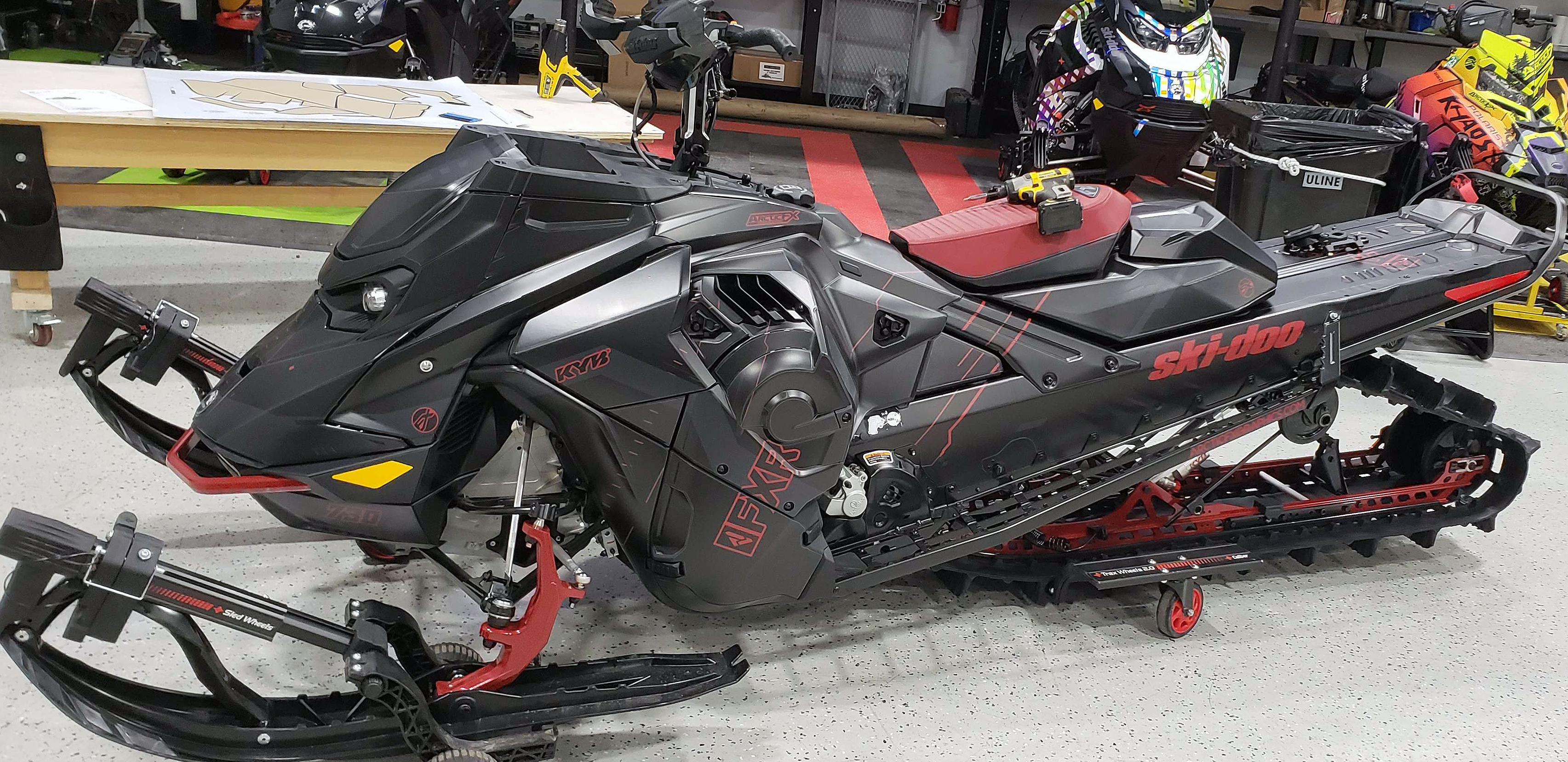 A Ski-Doo Gen5 Mountain snowmobile with a black and red solid color custom vinyl wrap.