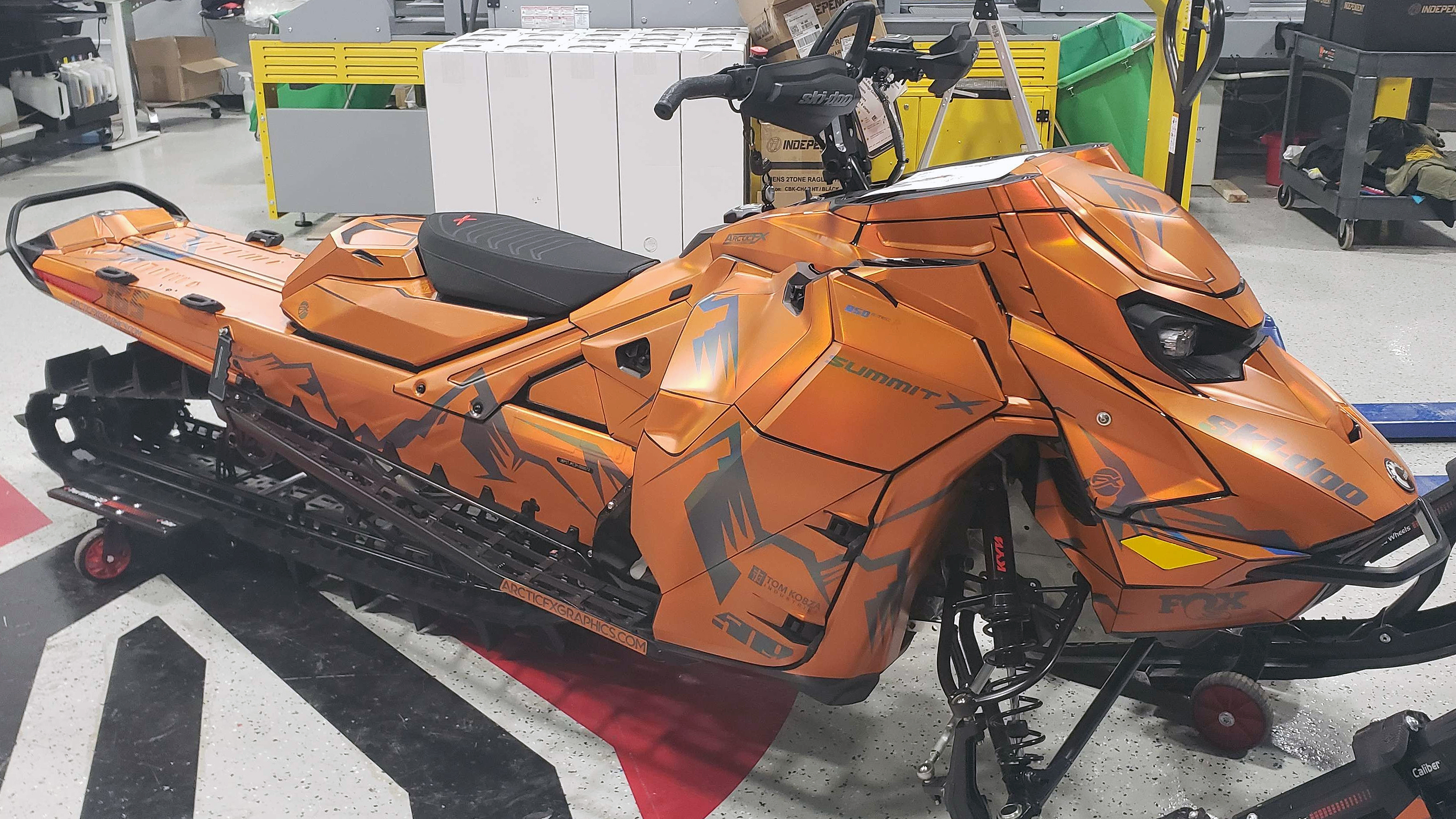 A Ski-Doo Gen5 Mountain snowmobile with a matte orange chrome solid color custom vinyl wrap.