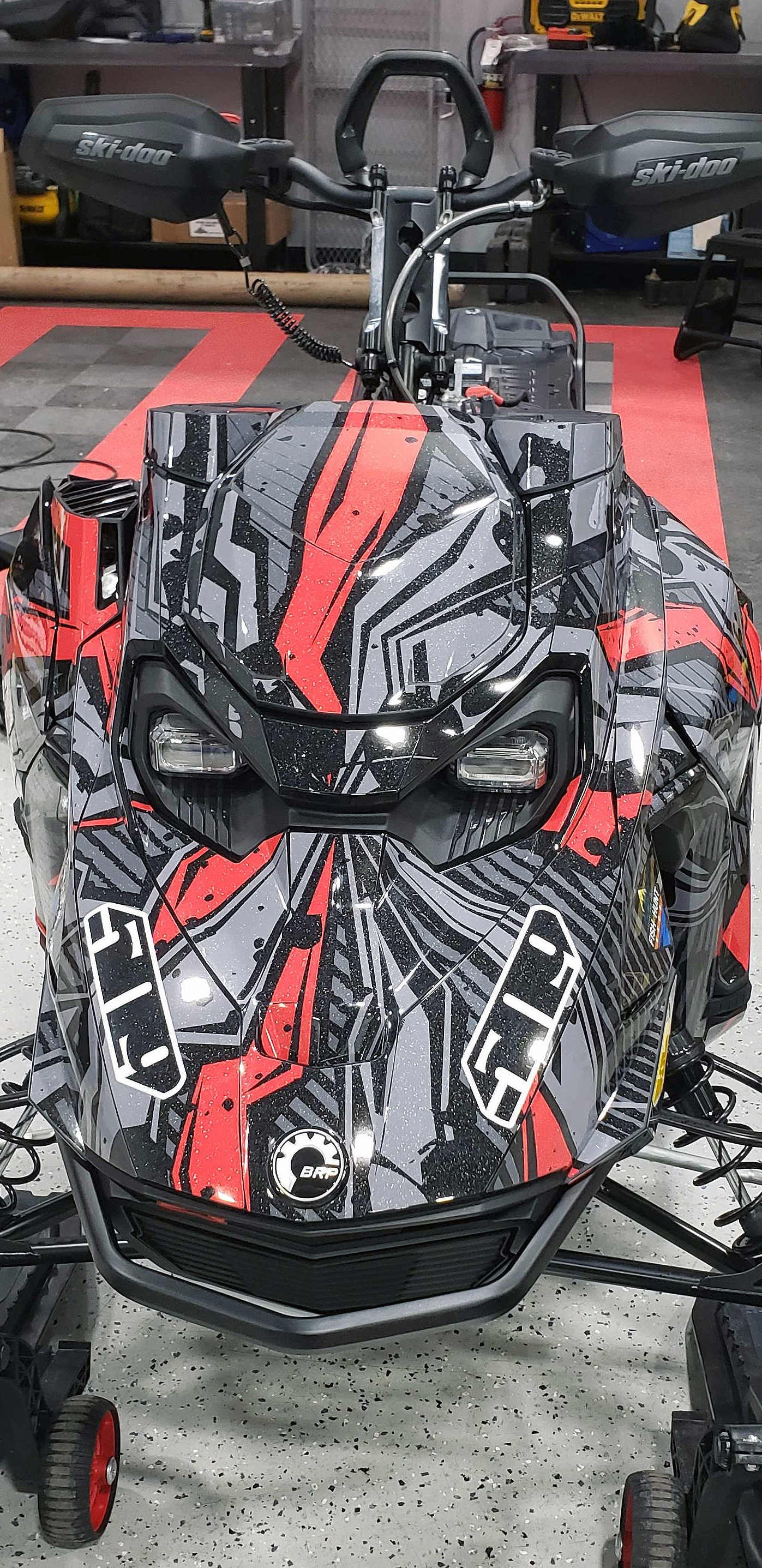 A Ski-Doo Gen5 Mountain snowmobile with a black, red, and gray Stricken custom vinyl wrap.