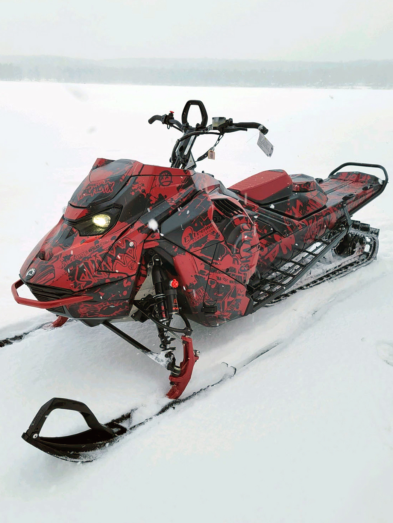 A Ski-Doo Gen5 Mountain snowmobile with a black and red Tagged custom vinyl wrap.