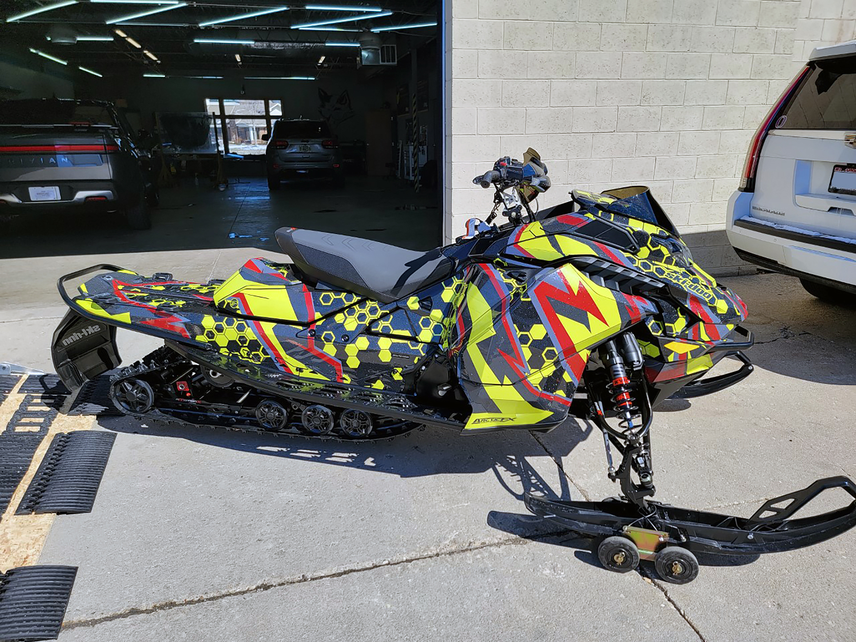 A Ski-Doo Gen5 Trail snowmobile with a red, lime squeeze, and black Cody Monroe Incision custom vinyl wrap.