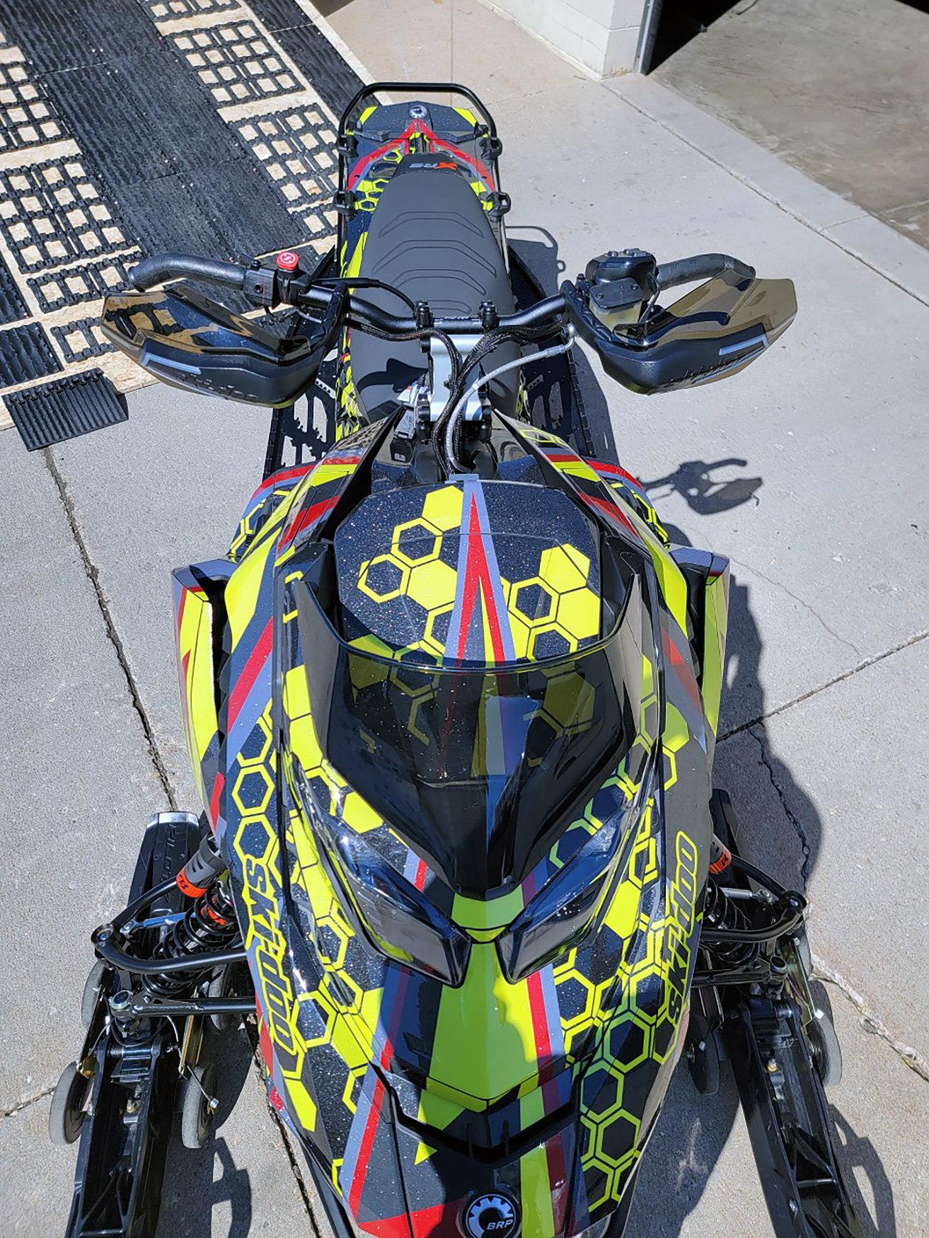 A Ski-Doo Gen5 Trail snowmobile with a red, lime squeeze, and black Cody Monroe Incision custom vinyl wrap.