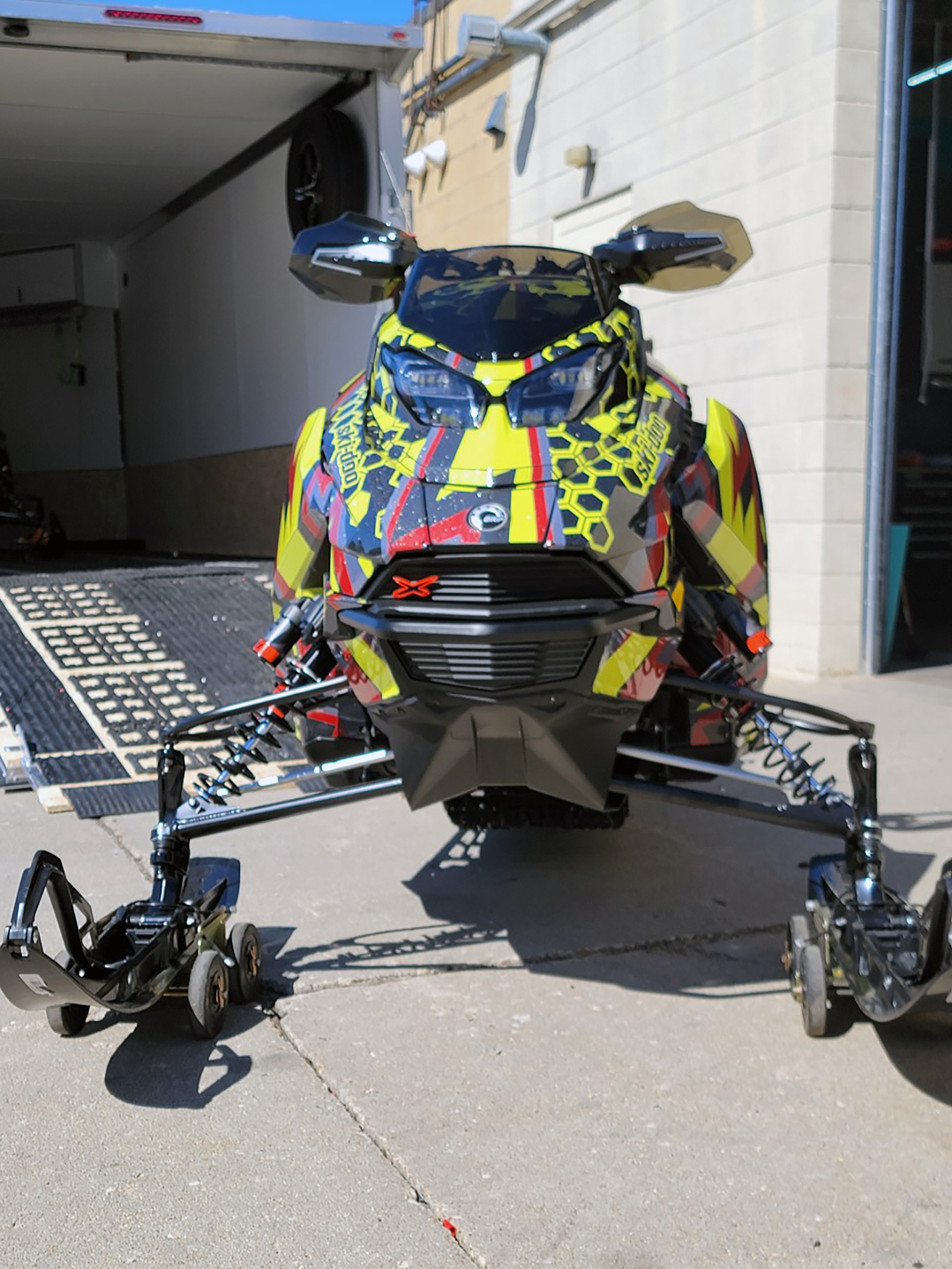 A Ski-Doo Gen5 Trail snowmobile with a red, lime squeeze, and black Cody Monroe Incision custom vinyl wrap.