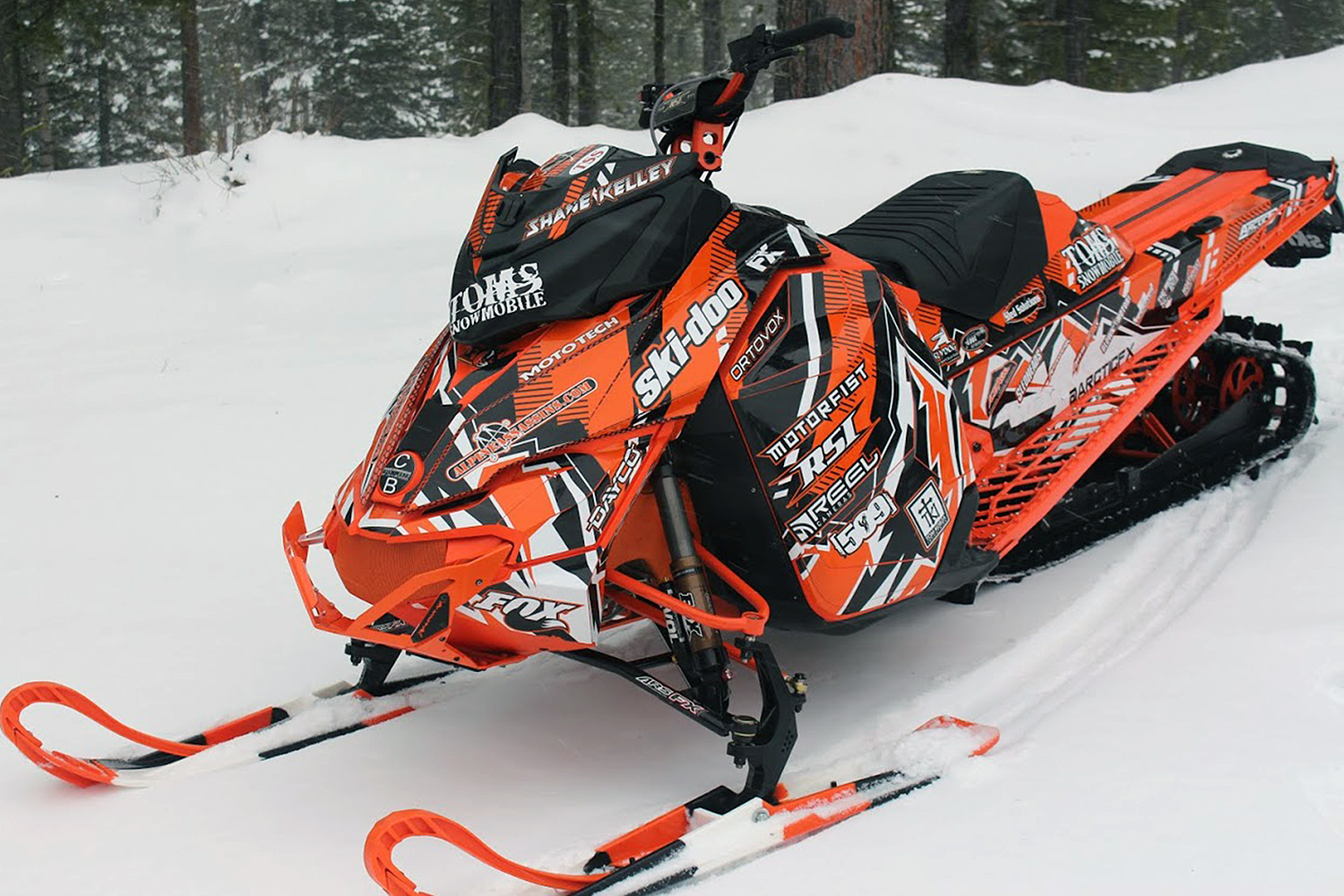 A Ski-Doo Rev XM snowmobile with a orange, white, and black Altitude City custom vinyl wrap.