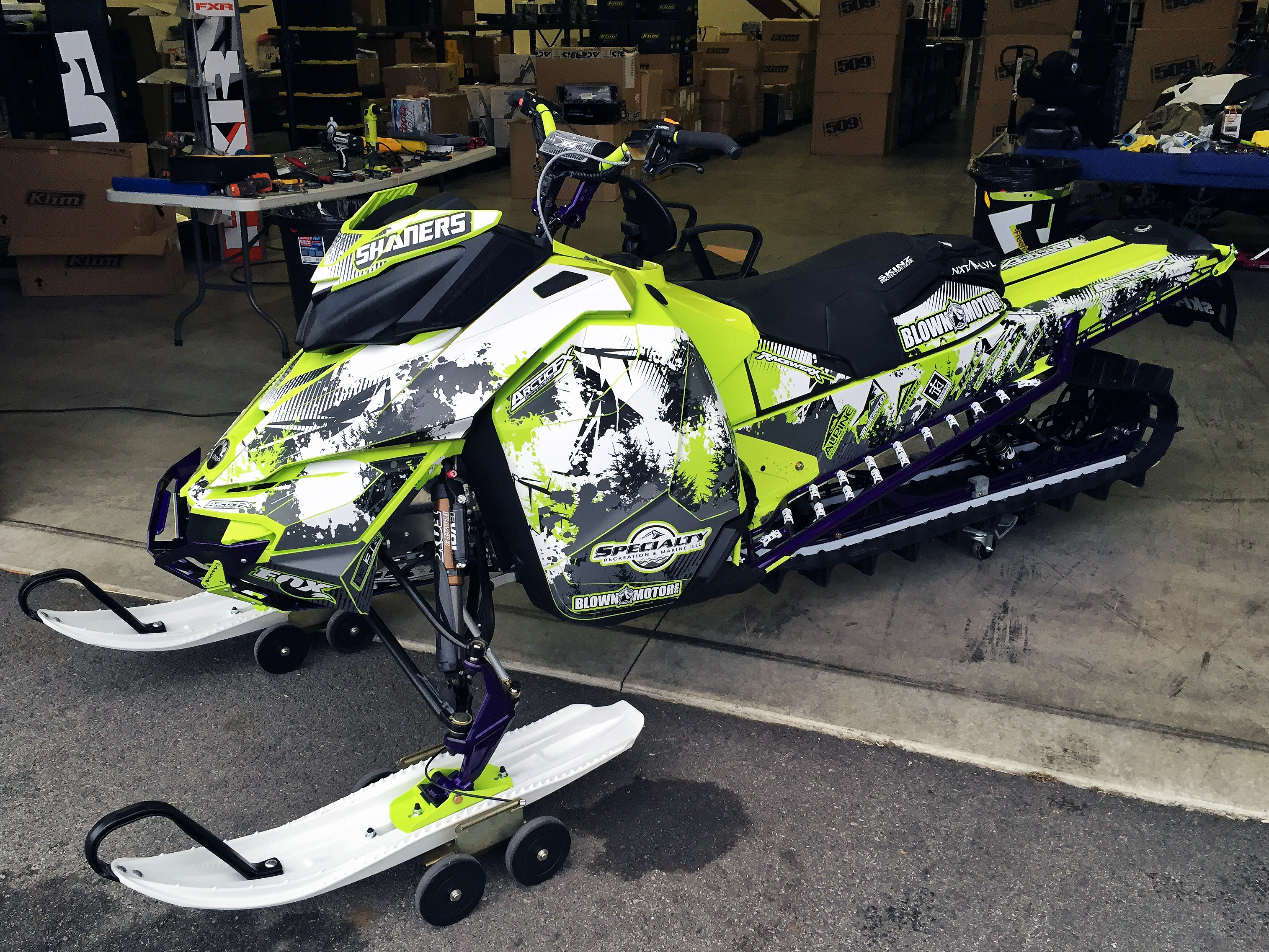 A Ski-Doo Rev XM snowmobile with a manta, white, and black Blown Motor custom vinyl wrap.