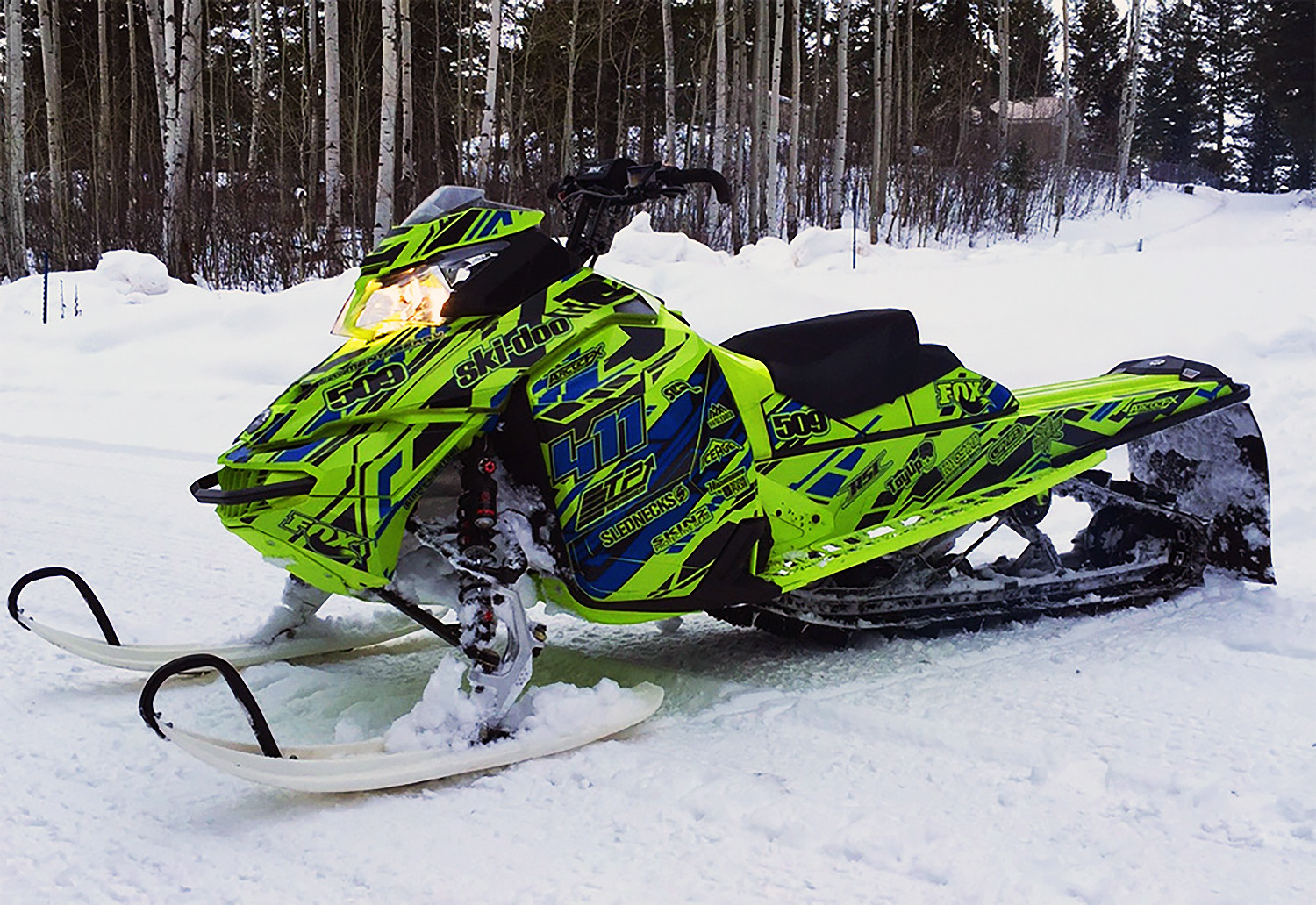 A Ski-Doo Rev XM snowmobile with a manta, blue, and black Evasion custom vinyl wrap.