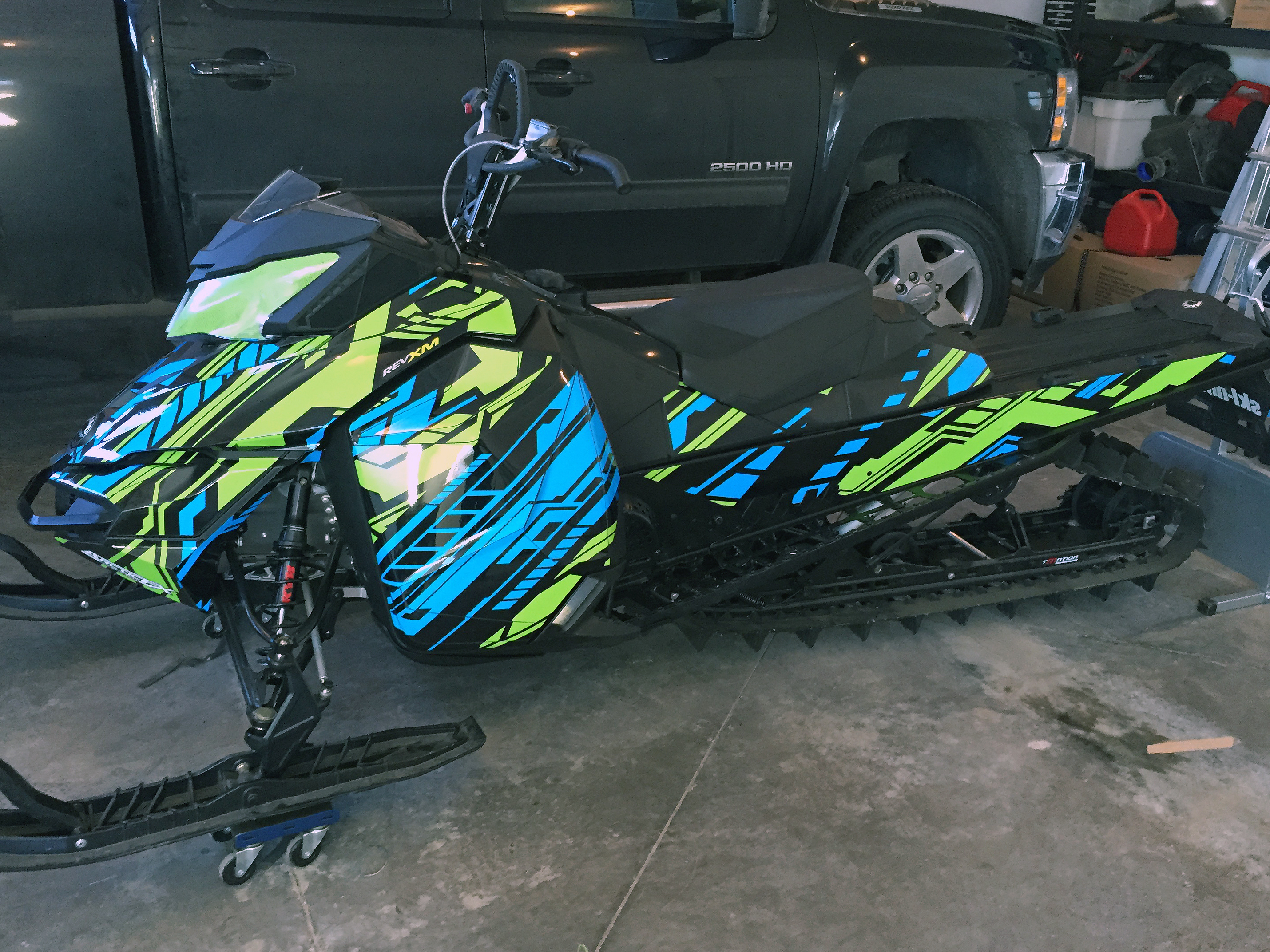 A Ski-Doo Rev XM snowmobile with a octane blue, manta, and black Evasion custom vinyl wrap.