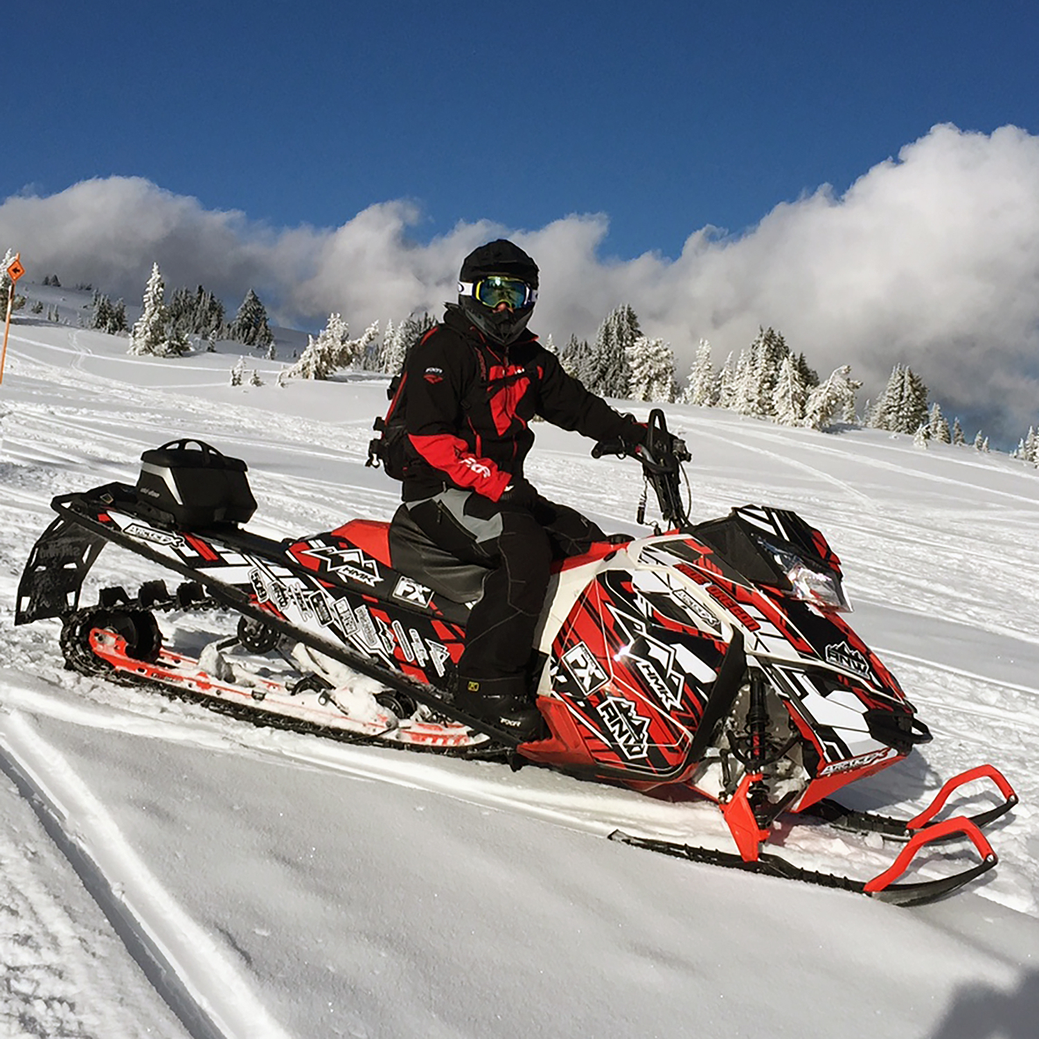 A Ski-Doo Rev XM snowmobile with a red, white, and black Evasion custom vinyl wrap.