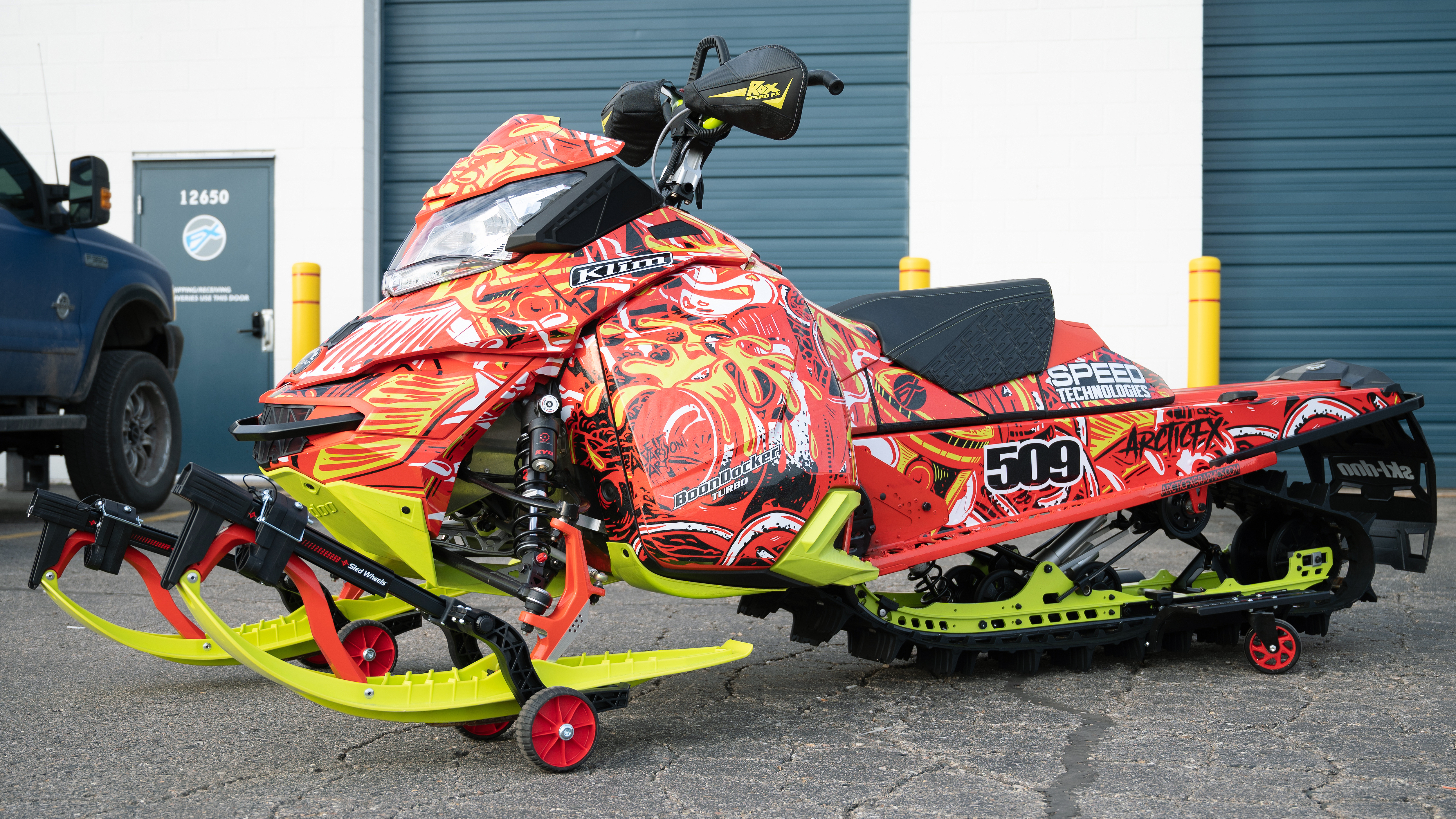 A Ski-Doo Rev XM snowmobile with a red, manta, and black Onasch Fueled custom vinyl wrap.