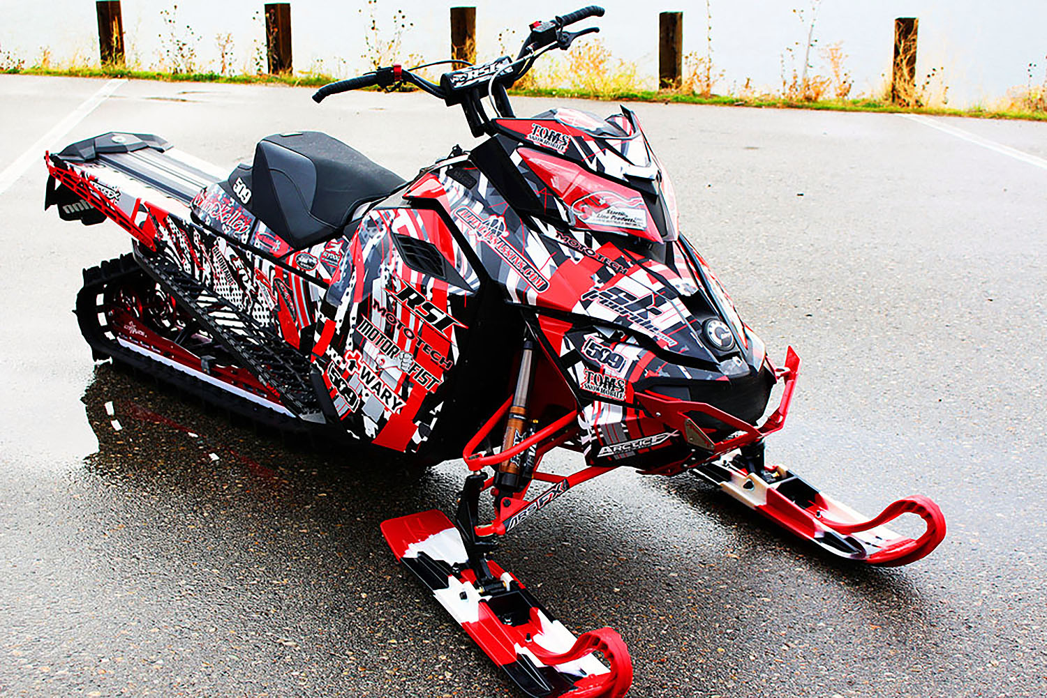 A Ski-Doo Rev XM snowmobile with a red, white, and black Kelley Arc Reactor custom vinyl wrap.