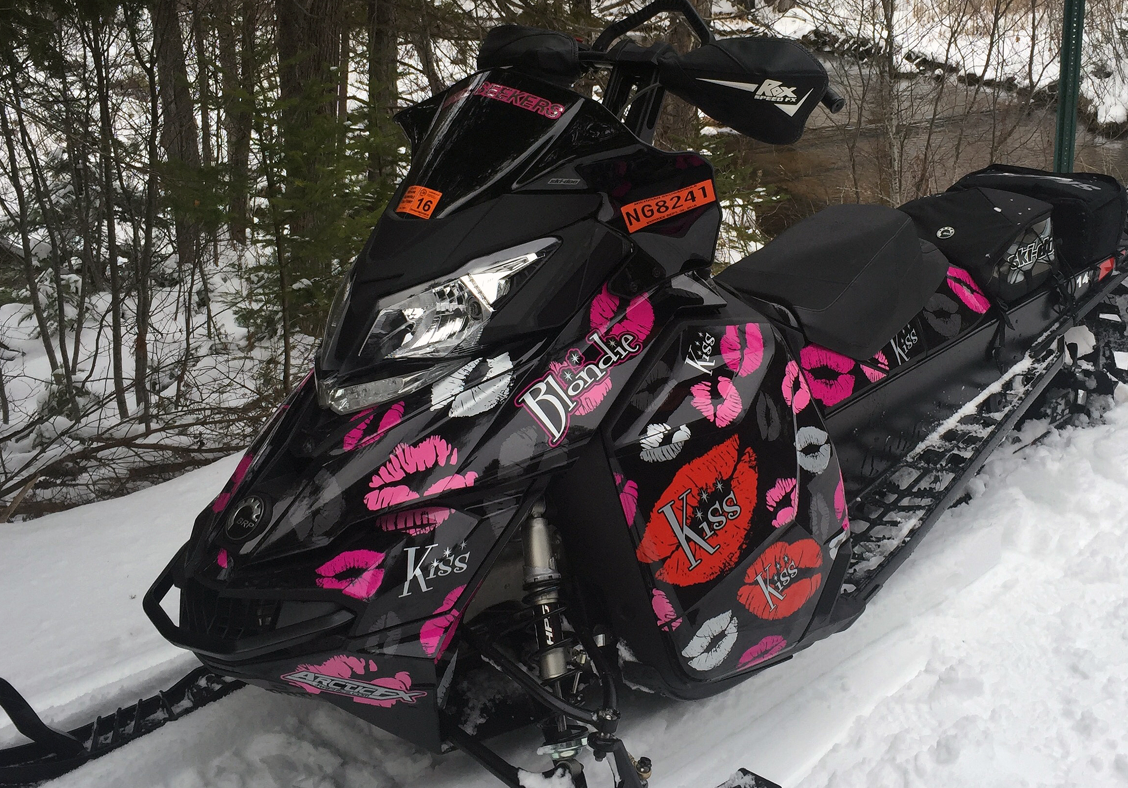 A Ski-Doo Rev XM snowmobile with a pink and black Lips Kiss custom vinyl wrap.