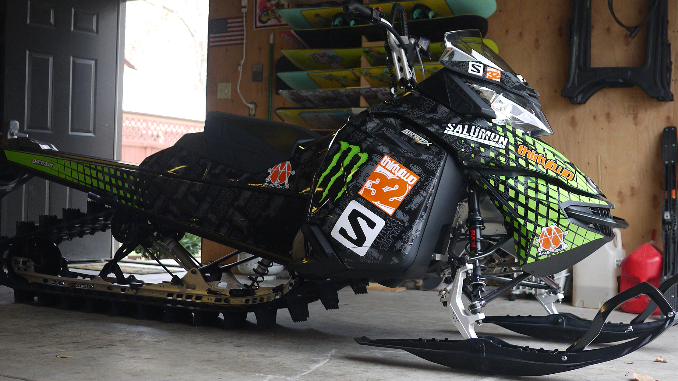 A Ski-Doo Rev XM snowmobile with a manta, gray, and black Monster custom vinyl wrap.