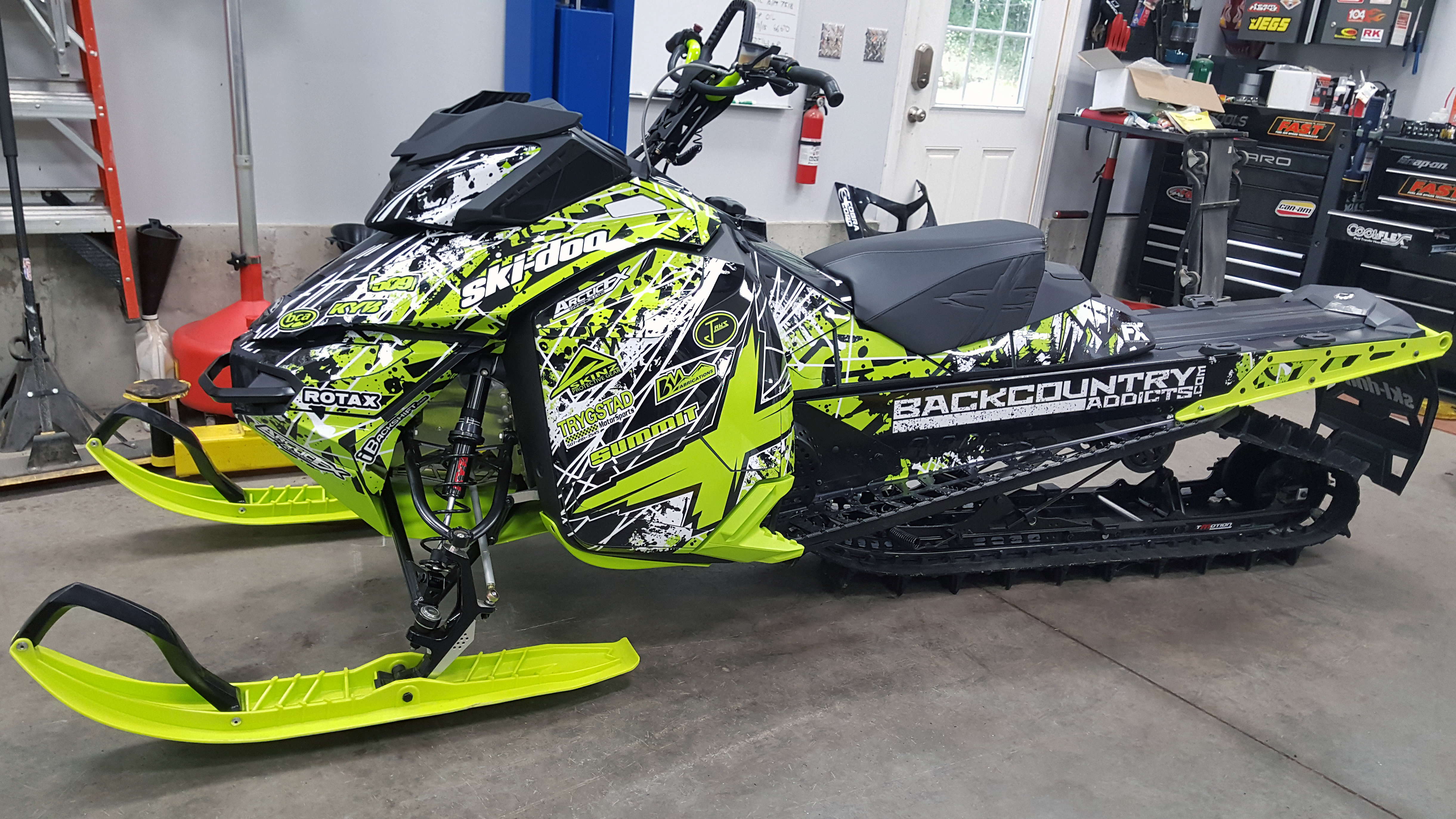 A Ski-Doo Rev XM snowmobile with a black, white, and manta Oblivion custom vinyl wrap.