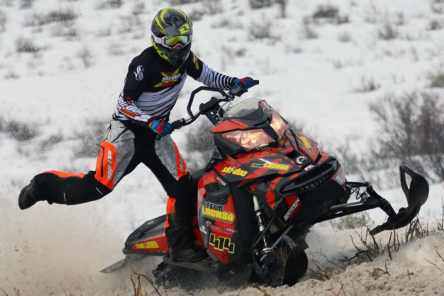 A Ski-Doo Rev XM snowmobile with a red and black Rising Sun custom vinyl wrap.