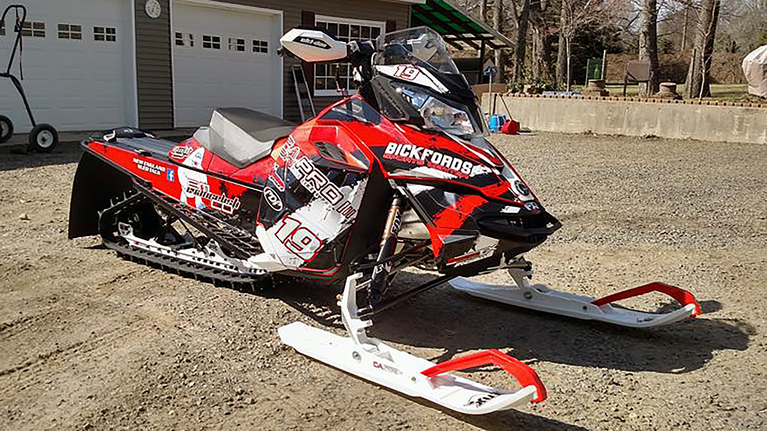A Ski-Doo Rev XM snowmobile with a red, white, and black Rising Sun custom vinyl wrap.