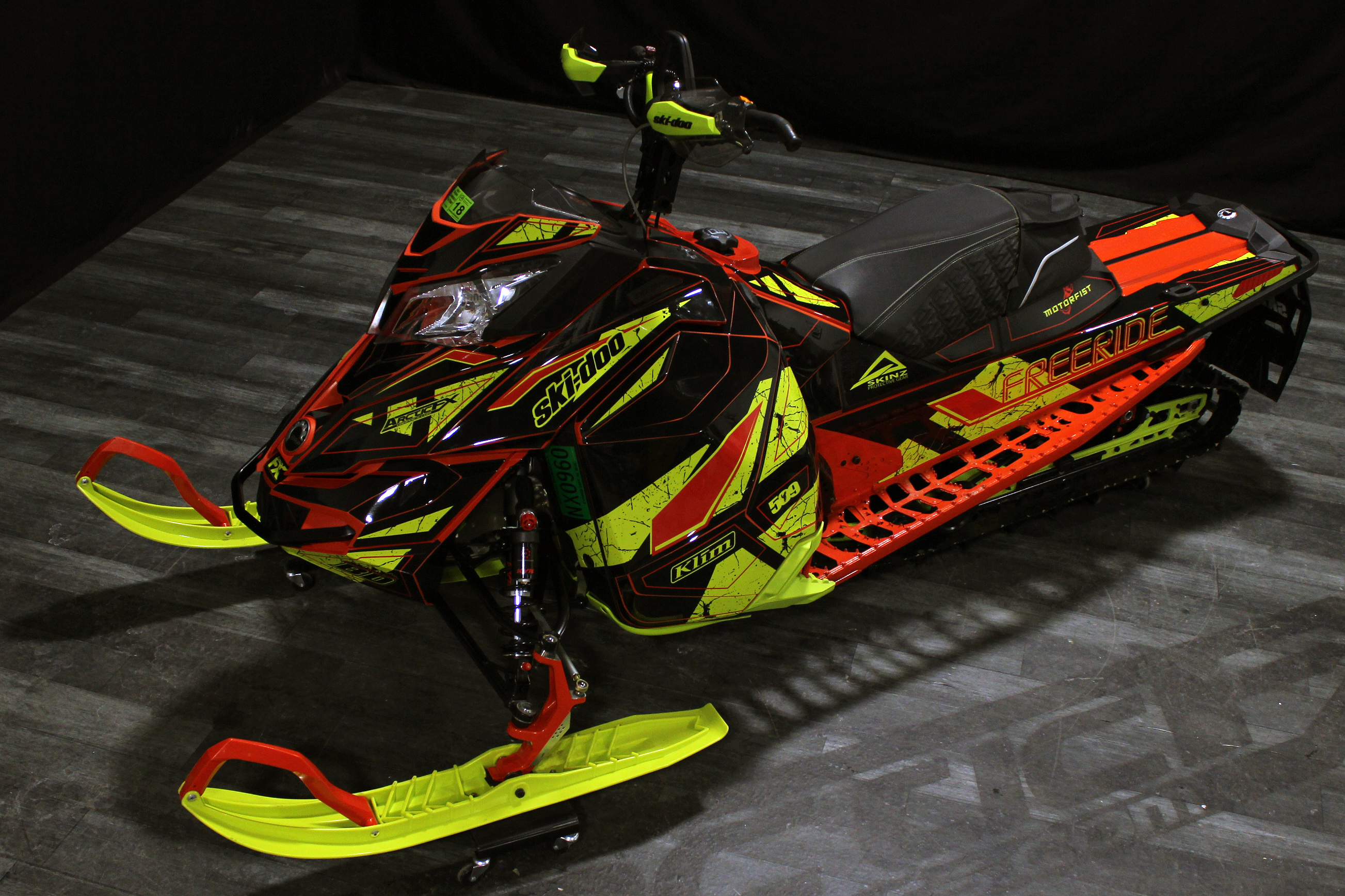 A Ski-Doo Rev XM snowmobile with a red, manta, and black Rogue custom vinyl wrap.