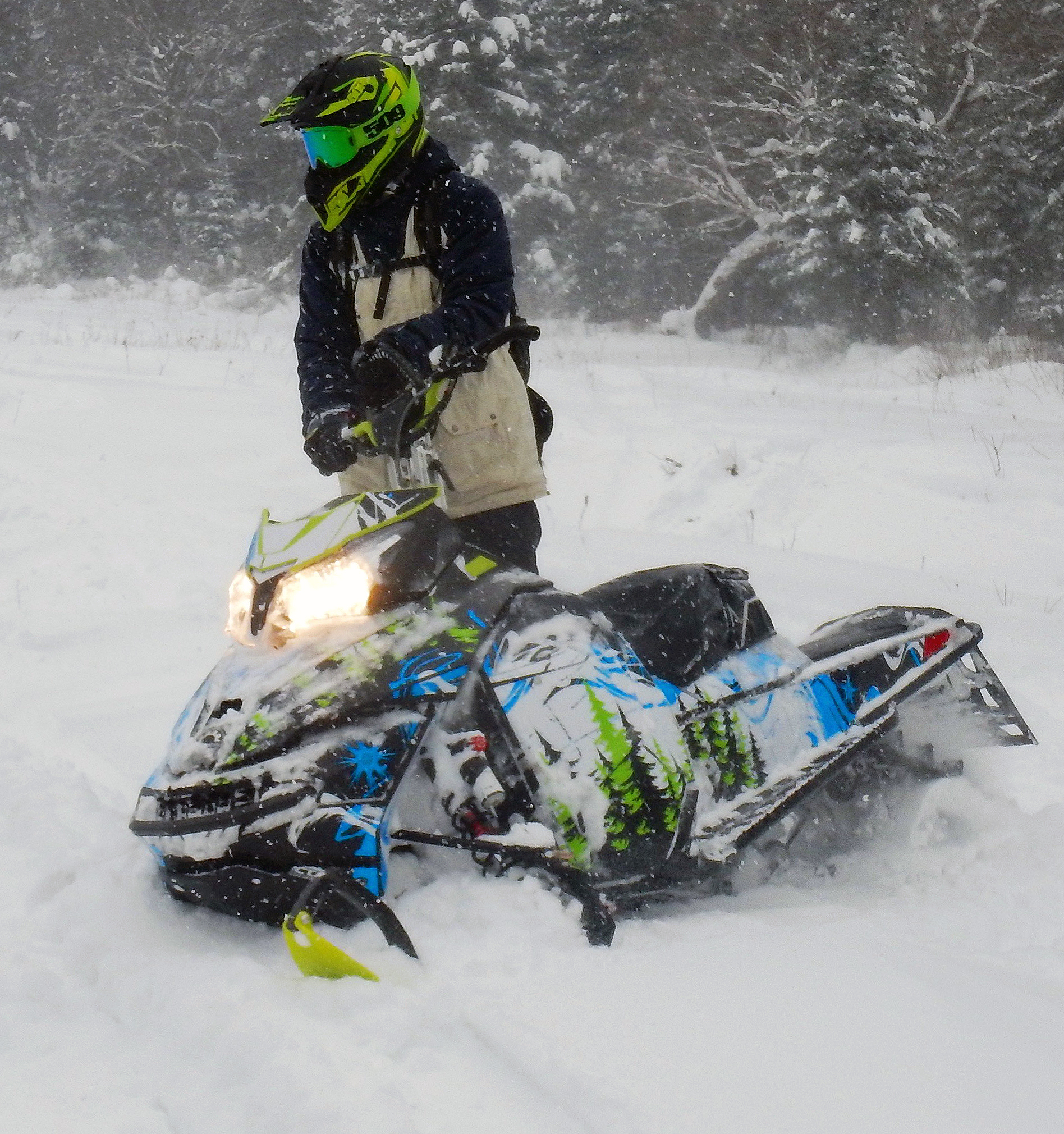 A Ski-Doo Rev XM snowmobile with a white, octane blue, and black Sub Zero custom vinyl wrap.