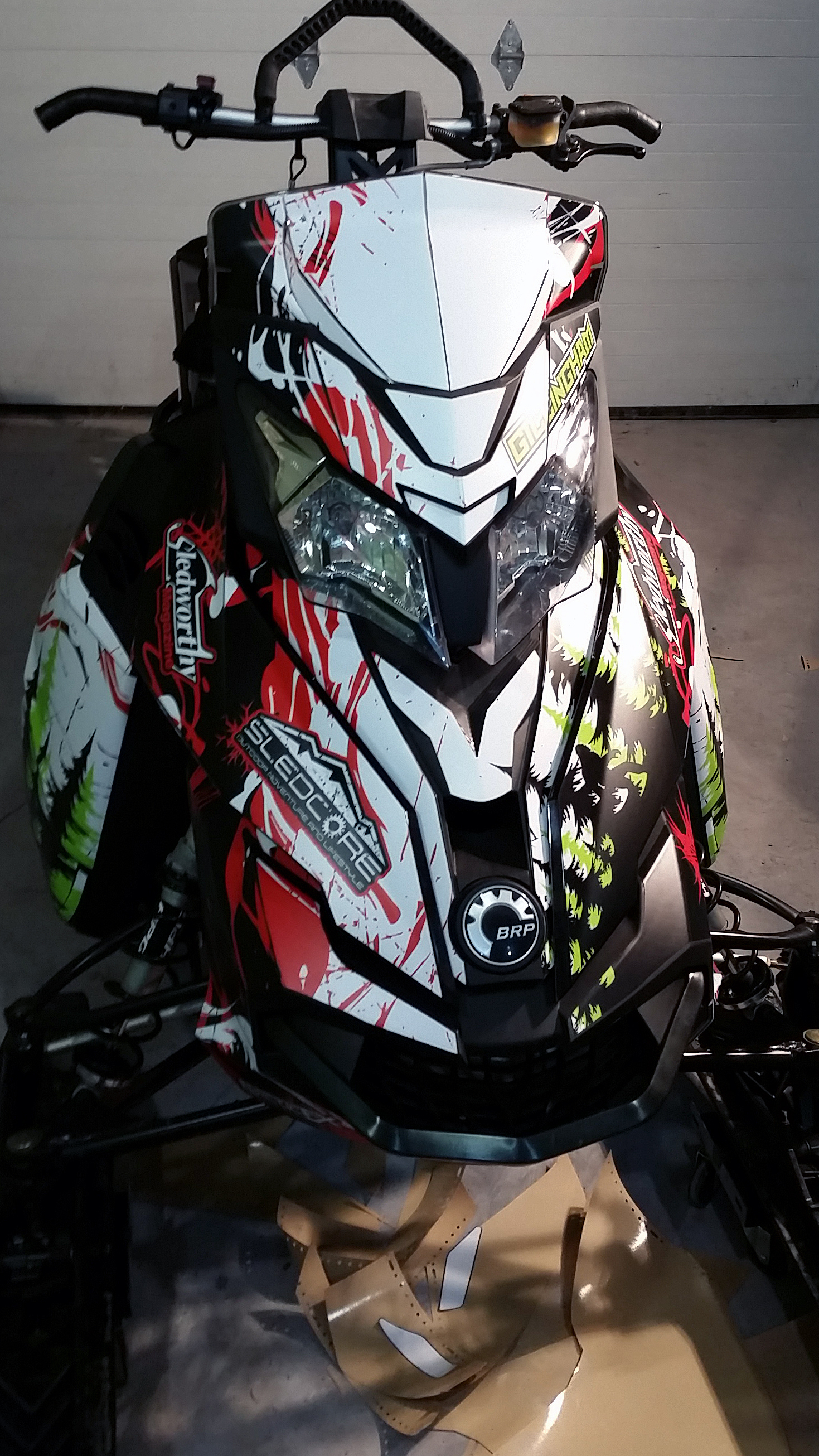 A Ski-Doo Rev XM snowmobile with a manta, red, and black Sub Zero custom vinyl wrap.