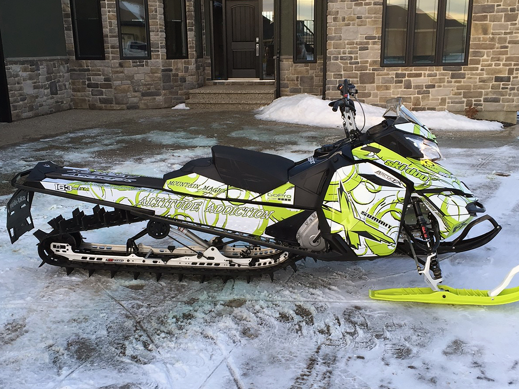 A Ski-Doo Rev XM snowmobile with a manta, white, and black Swirl custom vinyl wrap.