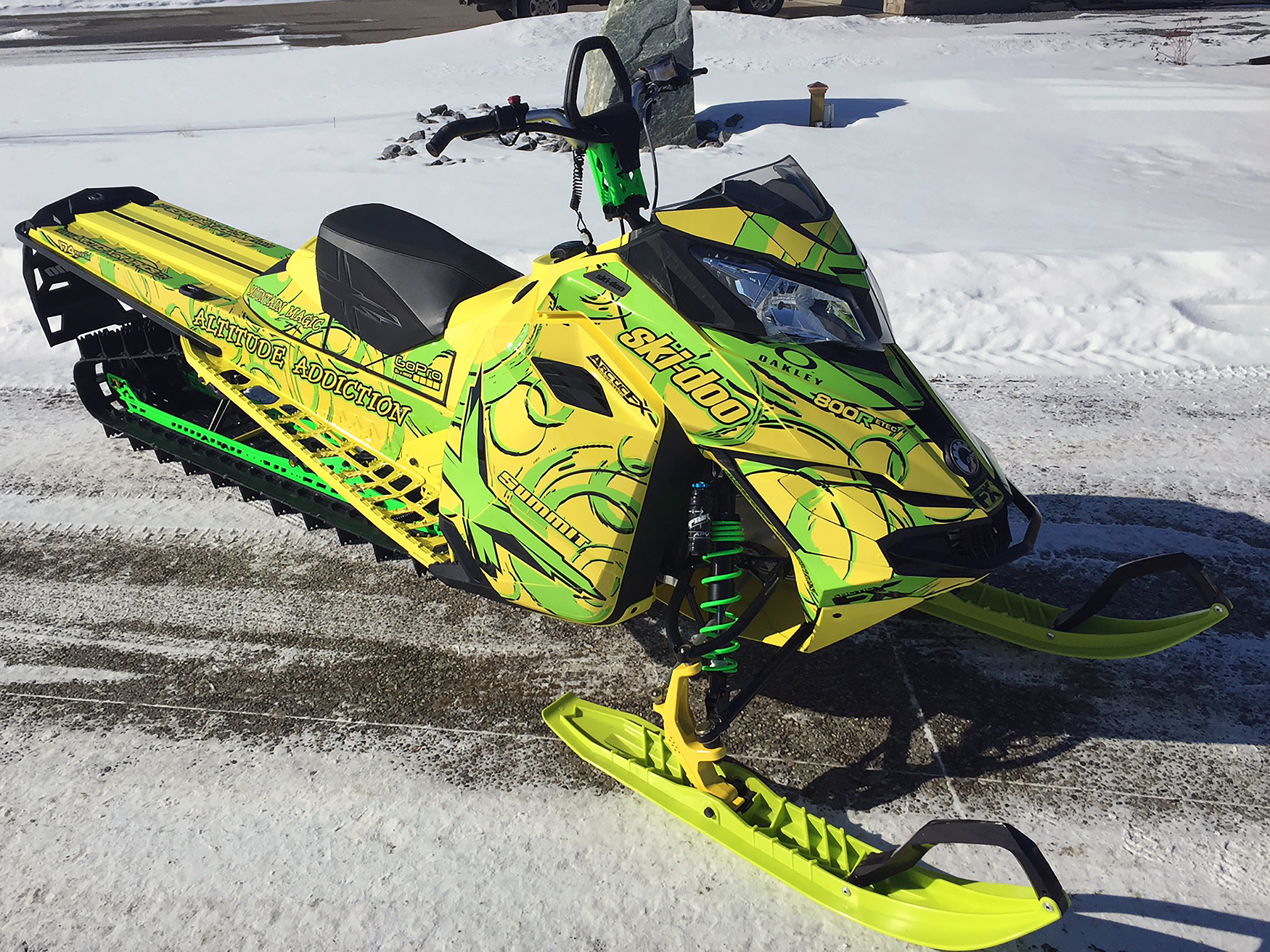 A Ski-Doo Rev XM snowmobile with a manta, yellow, and black Swirl custom vinyl wrap.