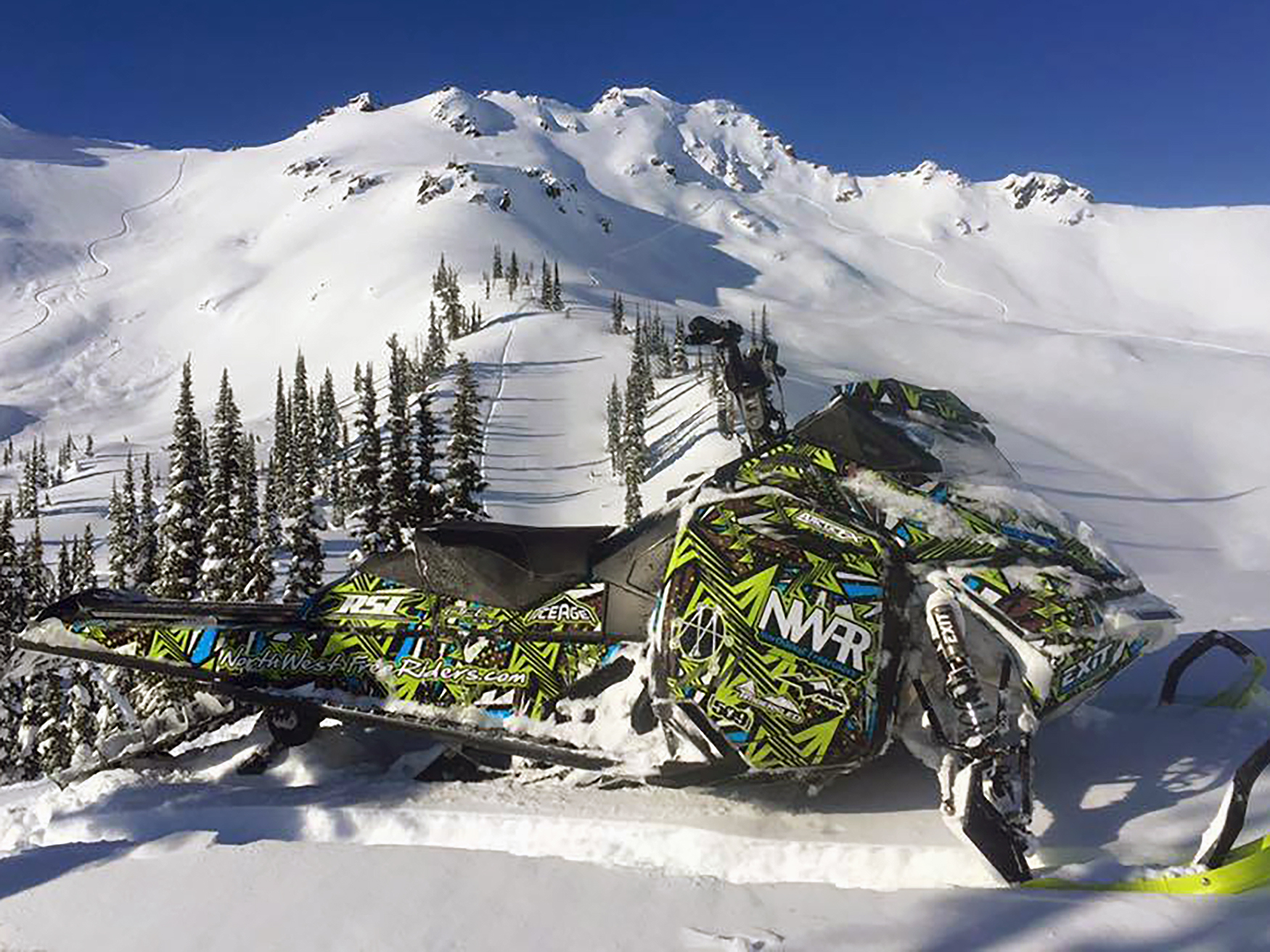 A Ski-Doo Rev XM snowmobile with a manta, octane blue, and white Twisted custom vinyl wrap.