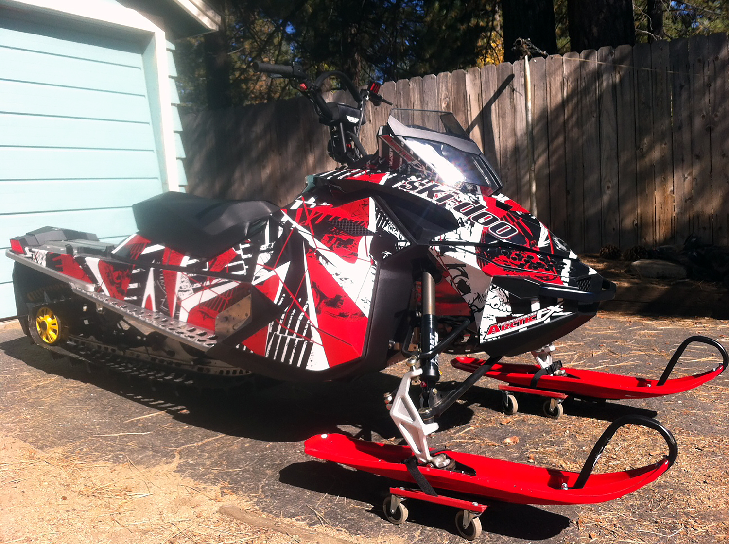 A Ski-Doo Rev XP snowmobile with a black, white, and red Broken Arrow custom vinyl wrap.