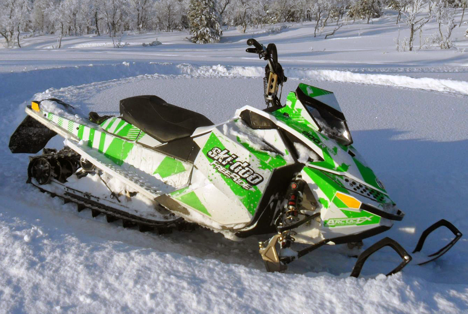 A Ski-Doo Rev XP snowmobile with a white and lime Hypnotize custom vinyl wrap.