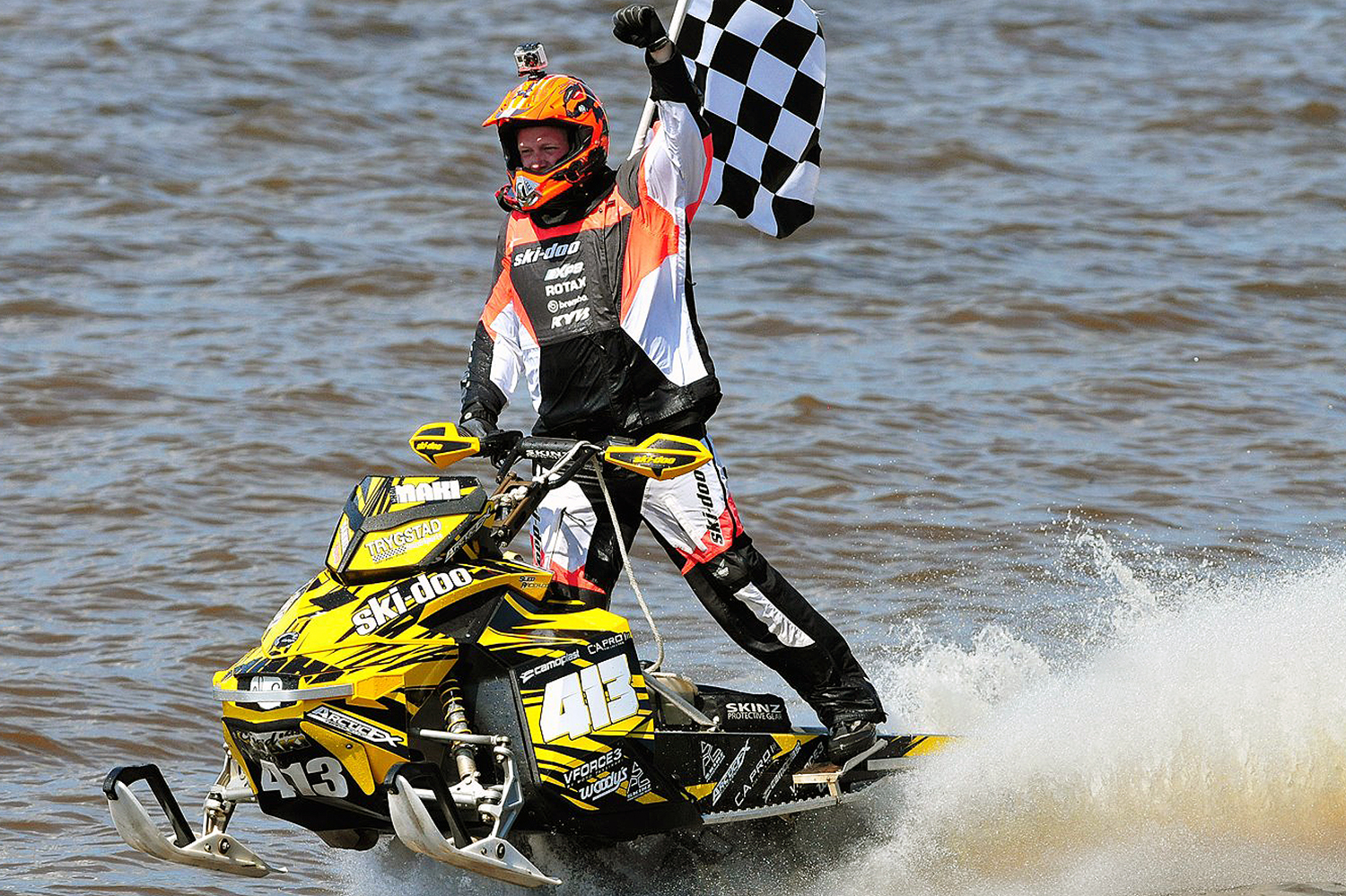 A Ski-Doo Rev XP snowmobile with a yellow and black Alpine custom vinyl wrap.