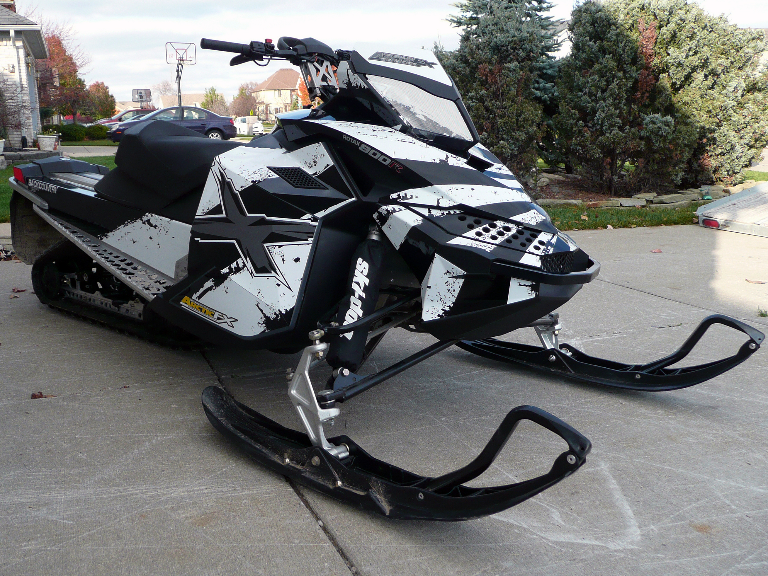 A Ski-Doo Rev XP snowmobile with a black and white Rising Sun custom vinyl wrap.
