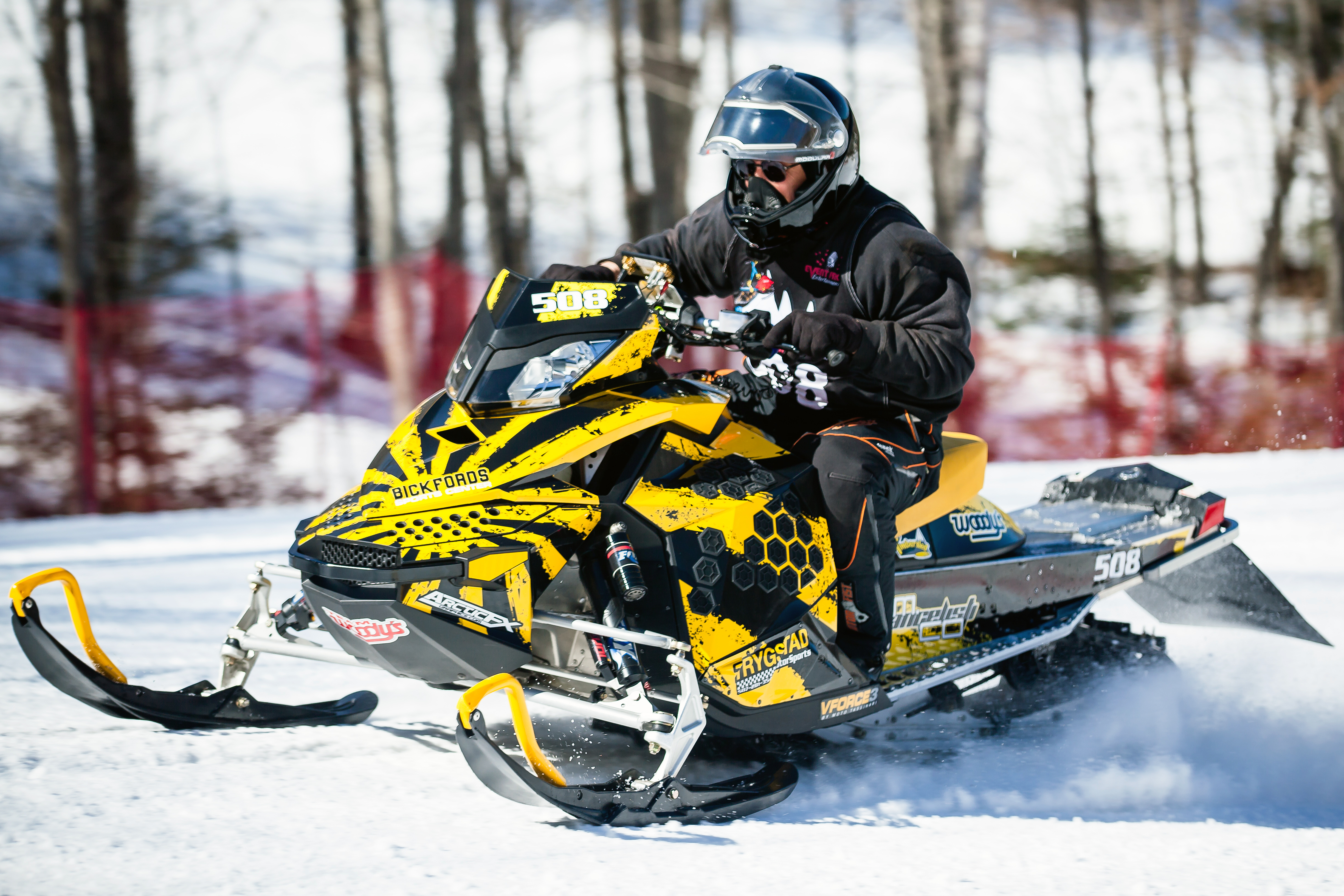 A Ski-Doo Rev XP snowmobile with a yellow and white Rising Sun custom vinyl wrap.