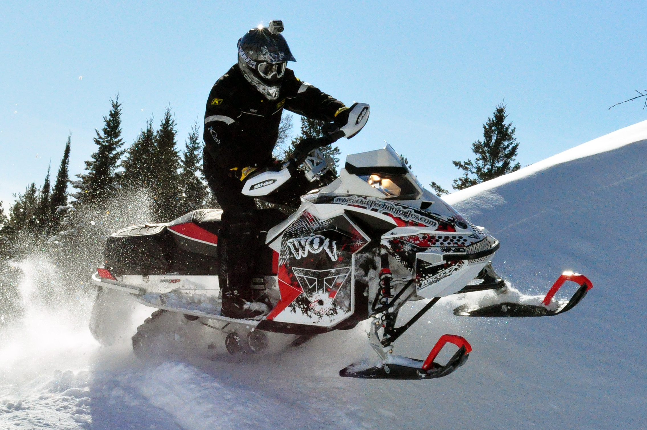 A Ski-Doo Rev XP snowmobile with a white, black, and red Snow Storm custom vinyl wrap.