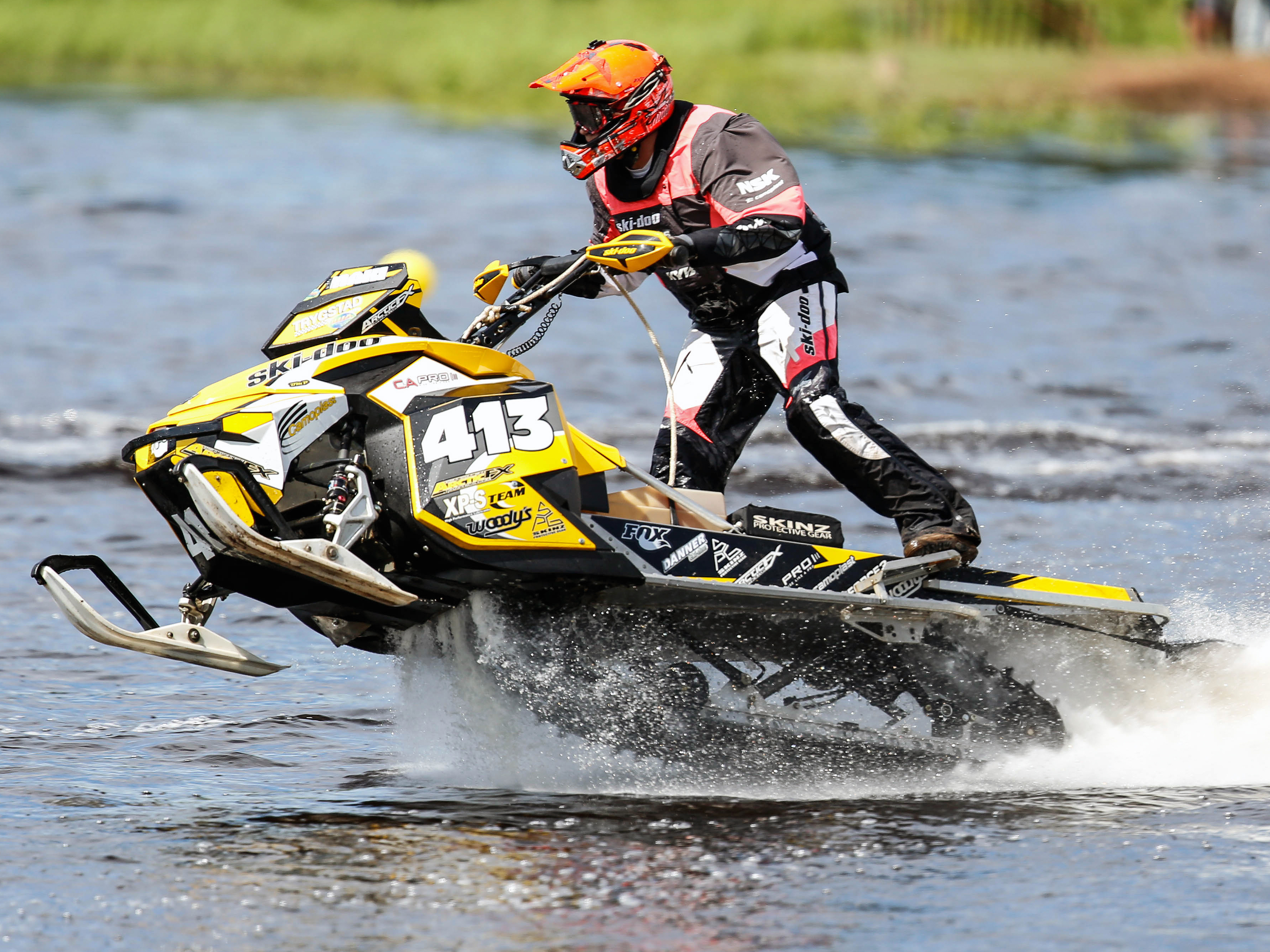 A Ski-Doo Rev XP snowmobile with a black, white, and yellow Team Maki custom vinyl wrap.